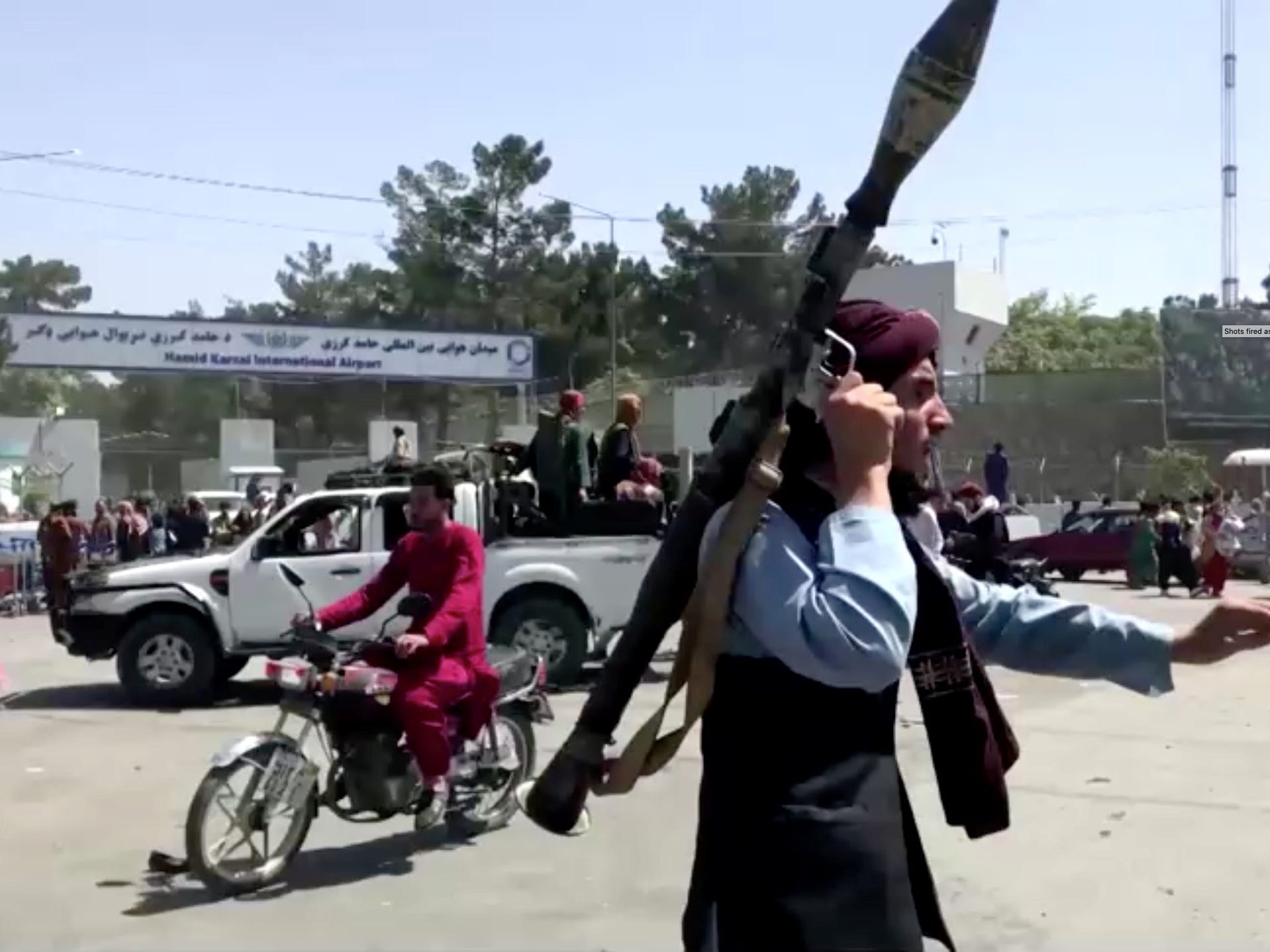 A Taliban fighter runs towards a crowd outside Kabul airport.