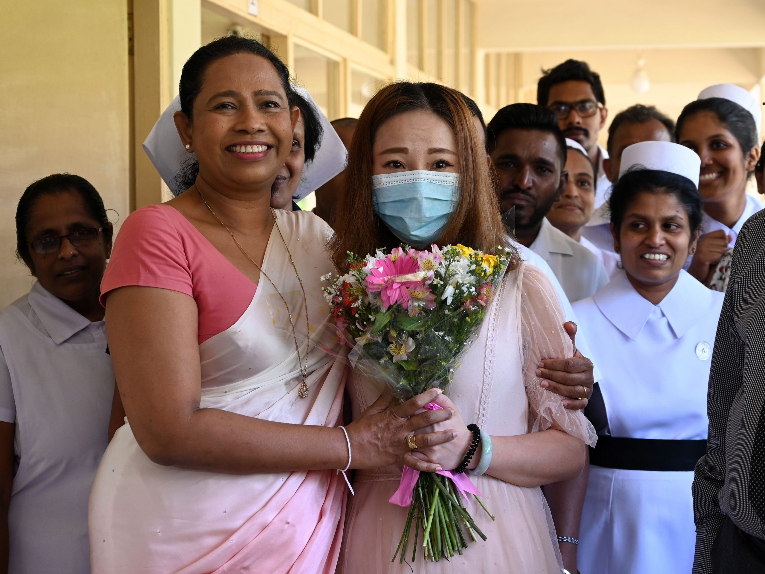 Former Sri Lankan Health Minister Pavithra Wanniarachchi poses with a Chinese tourist who was  discharged from a hospital after contracting COVID. The photo was taken at the main infectious diseases hospital near Colombo on February 19, 2020, following her recovery.
