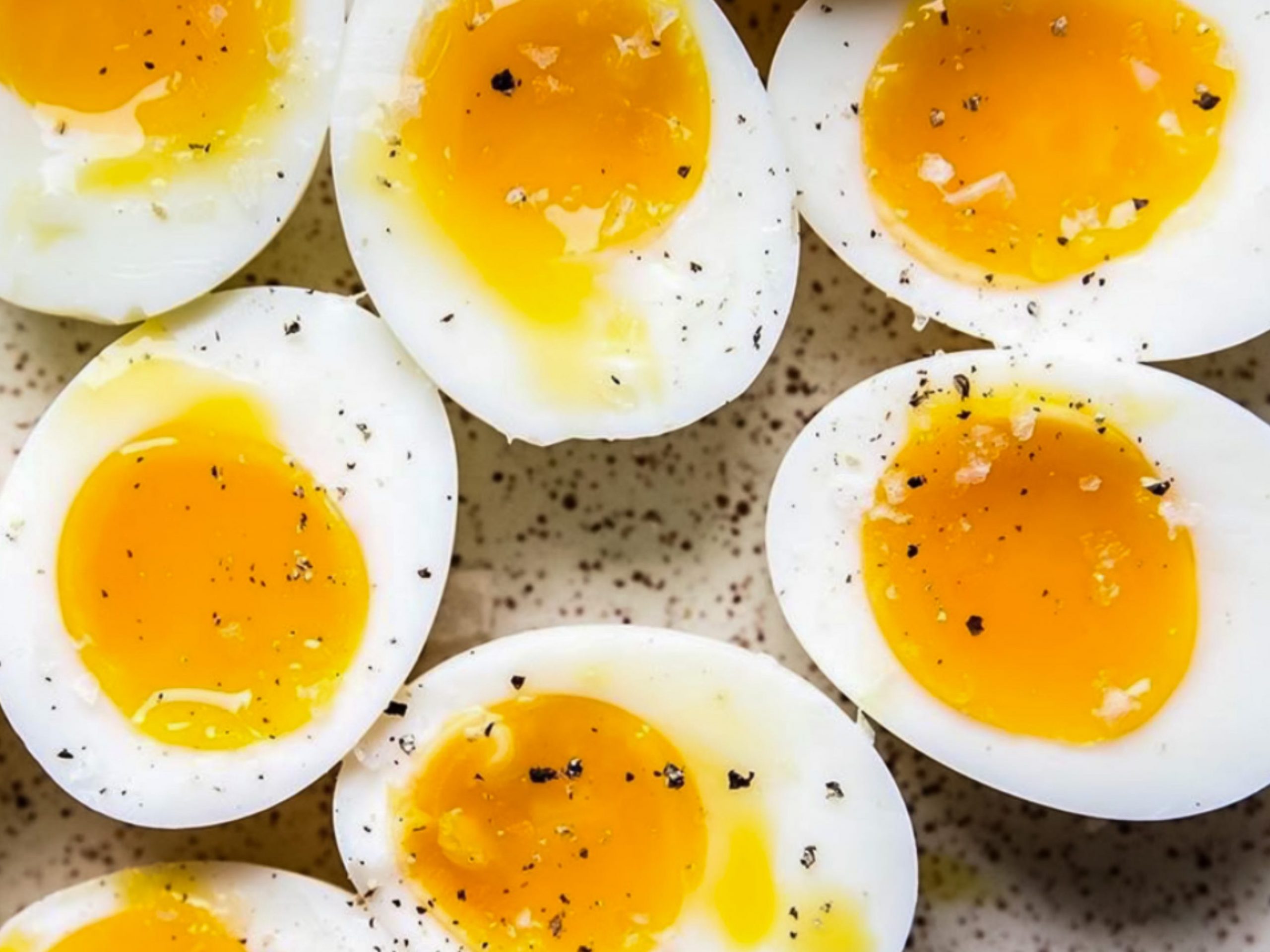Several medium-boiled eggs sliced open with yolks oozing
