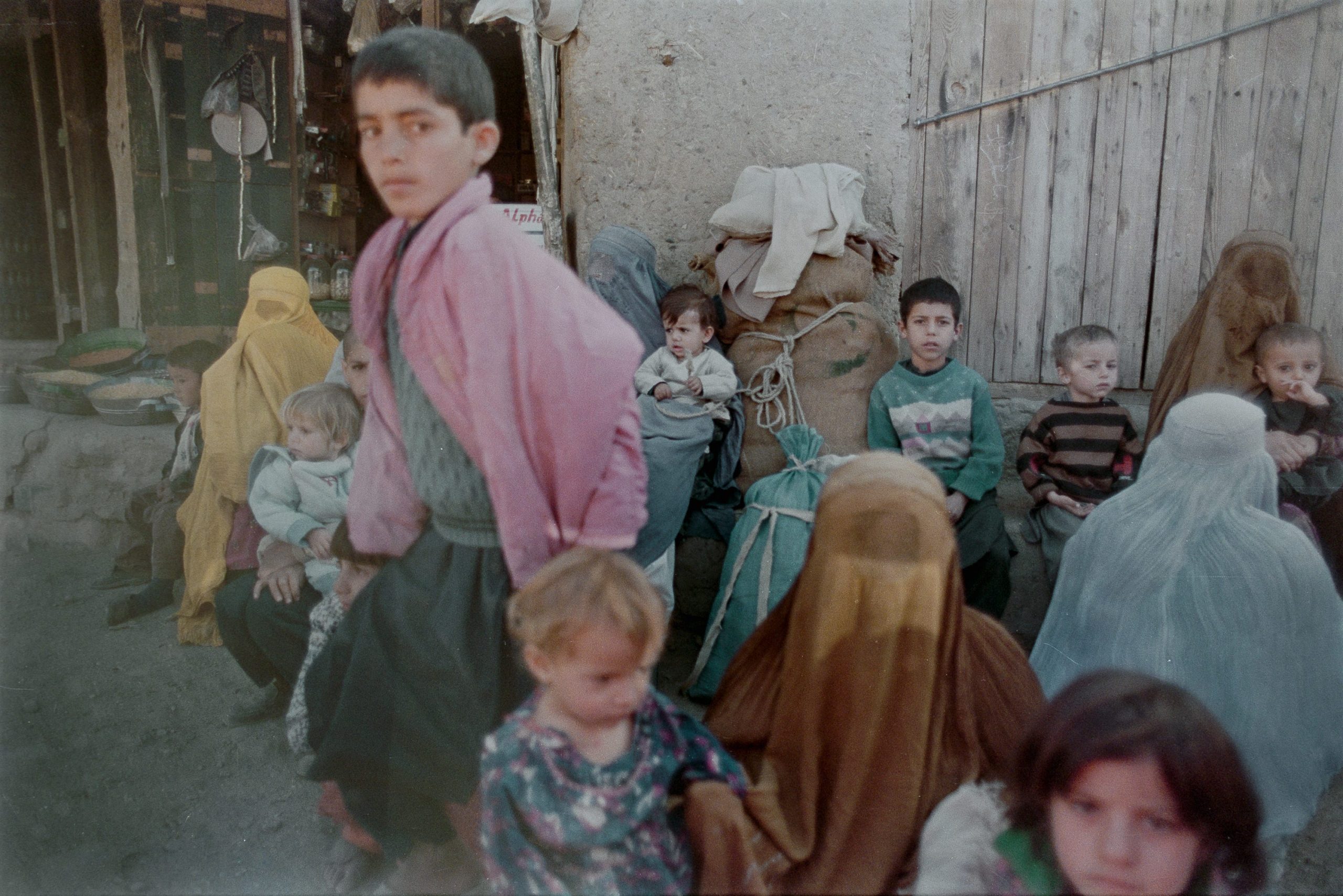 A crowd of boys are seen amid older women, who are fully covered in religious clothing.