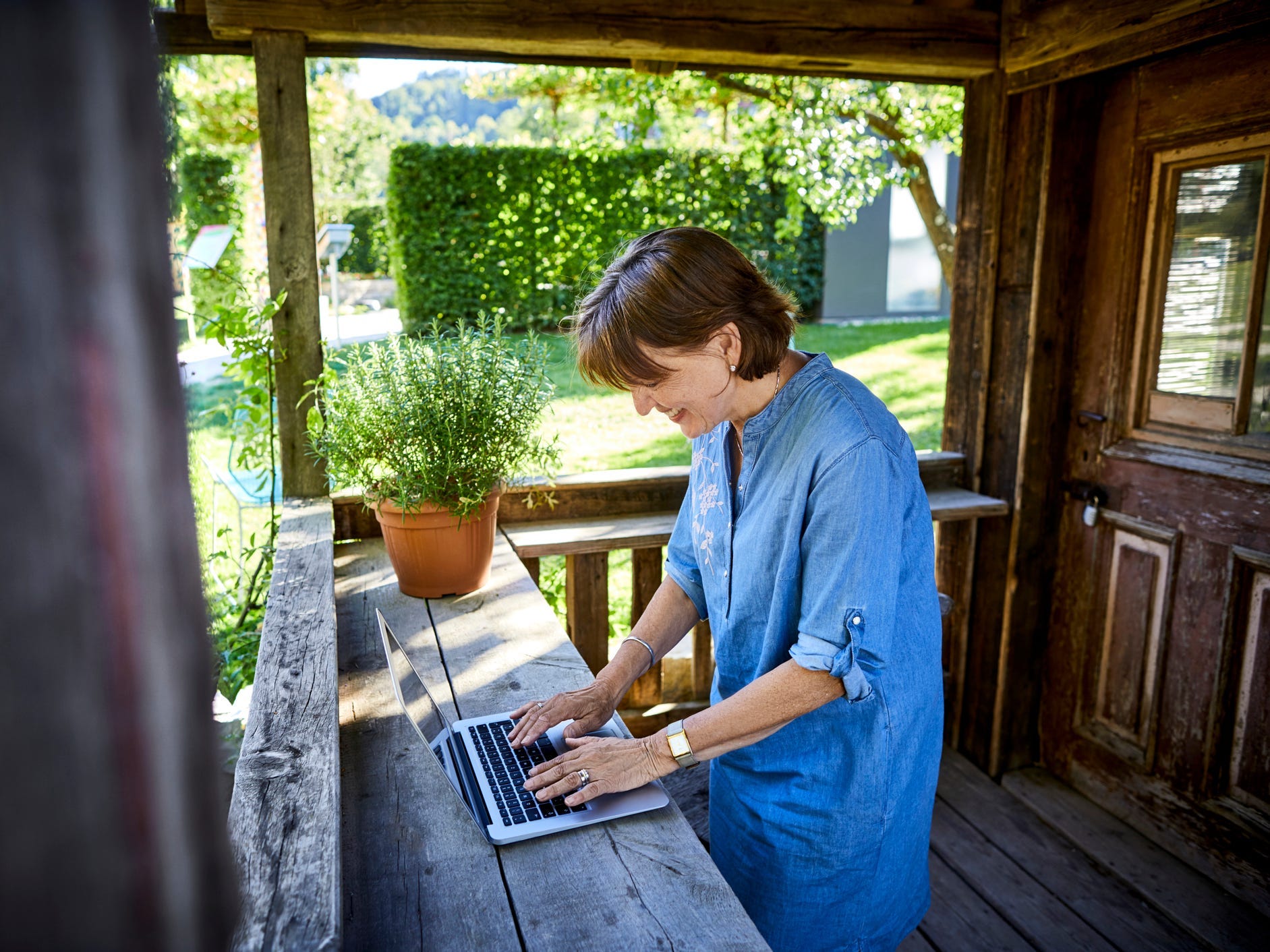 A woman standing and working on a laptop on her front porch