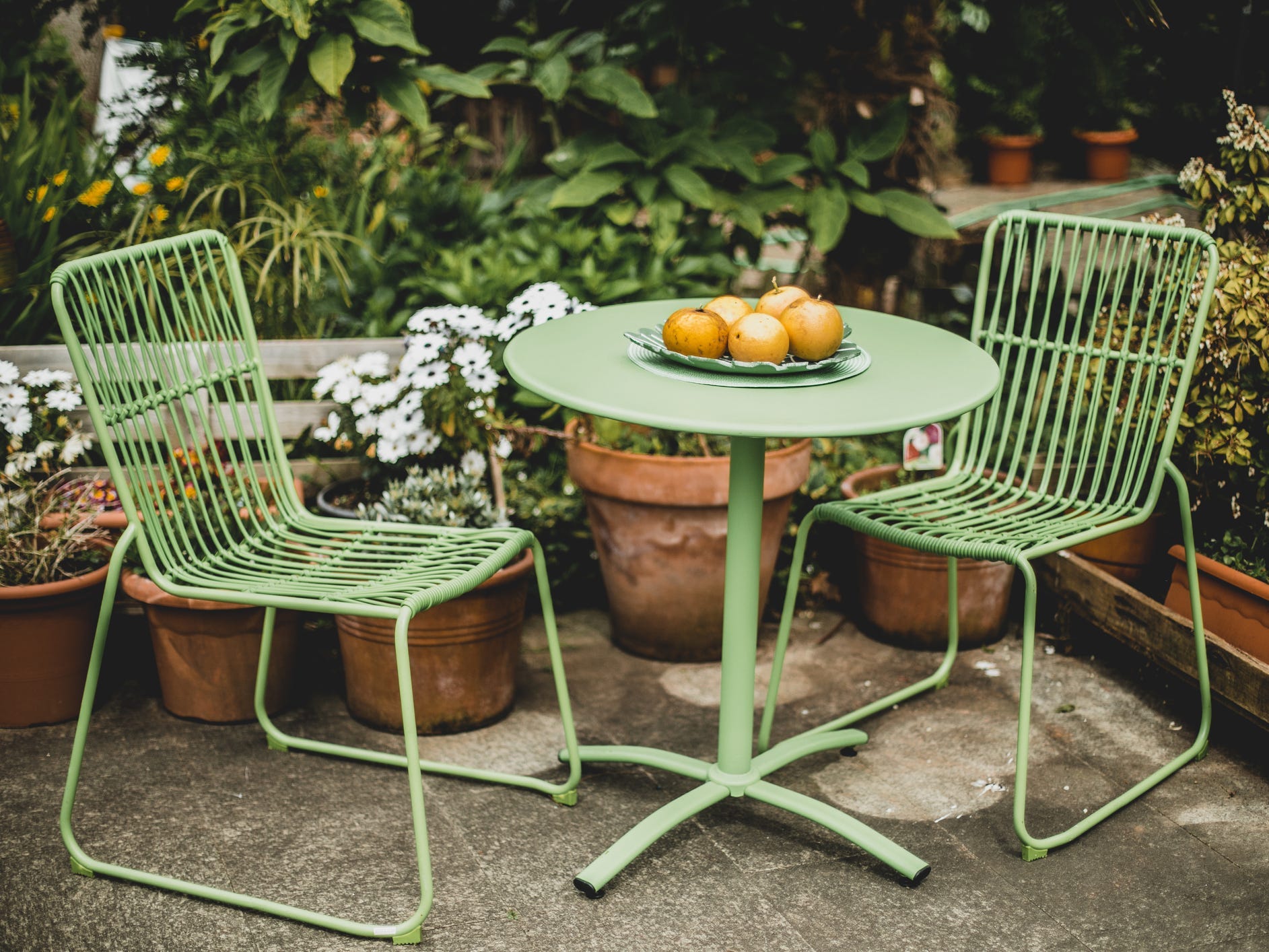 A green bistro table and chairs in a garden