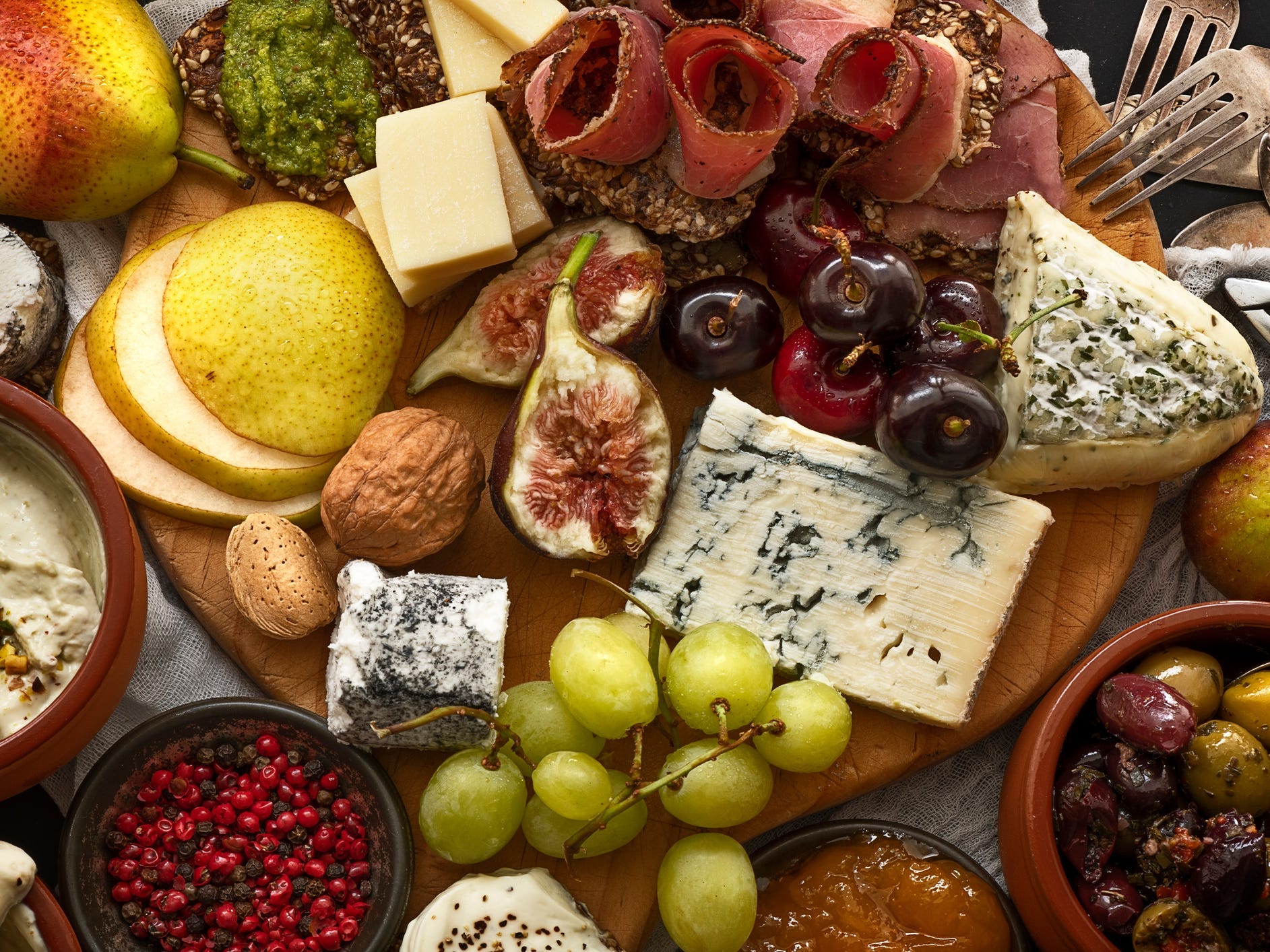 A charcuterie board with meats, cheeses, and fruits.