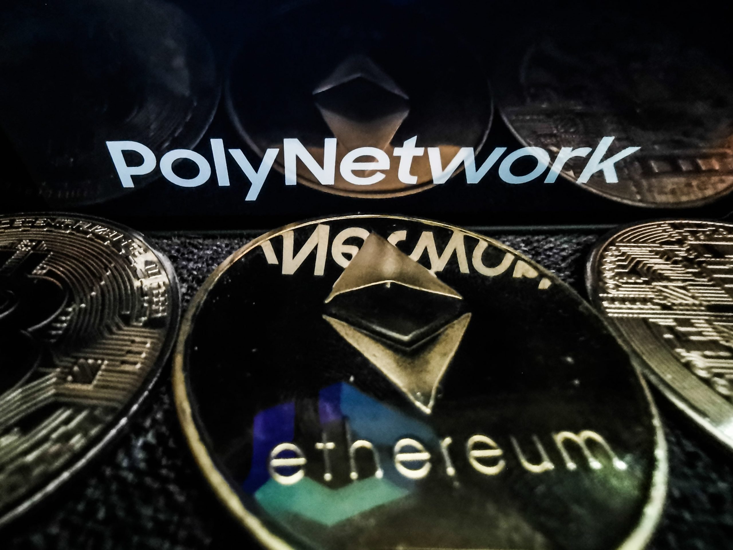 Poly Network logo displayed on a phone screen and representation of Ethereum cryptocurrency is seen in this illustration photo taken in Sulkowice, Poland on August 12, 2021.