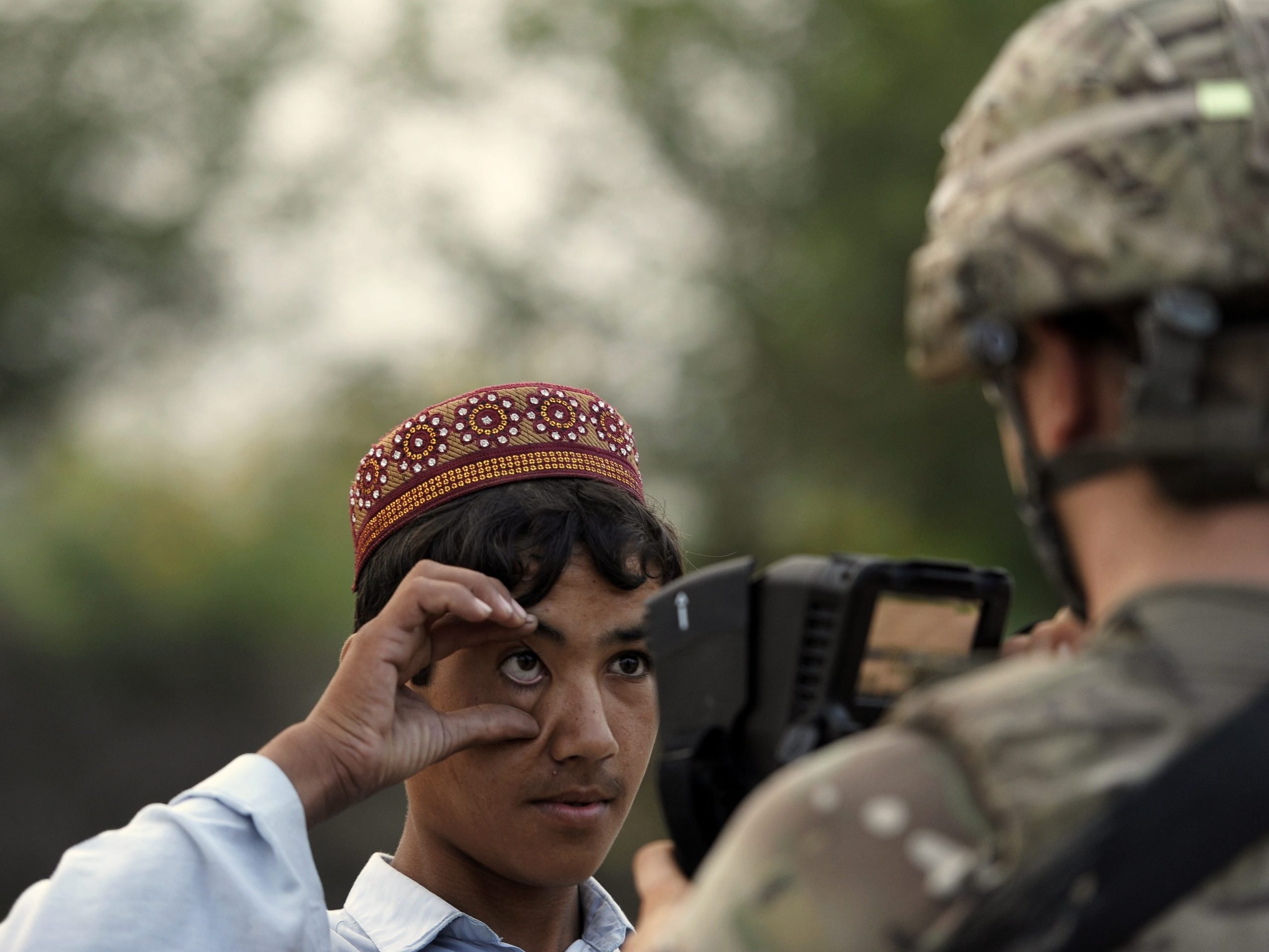 An American ISAF solider from team Apache of Task Force Geronimo, 4th Platoon Delaware of the United States Army, collects biometric information from an Afghan villager in the village of Mans Kalay in Sabari, Khost district on August 4, 2012.