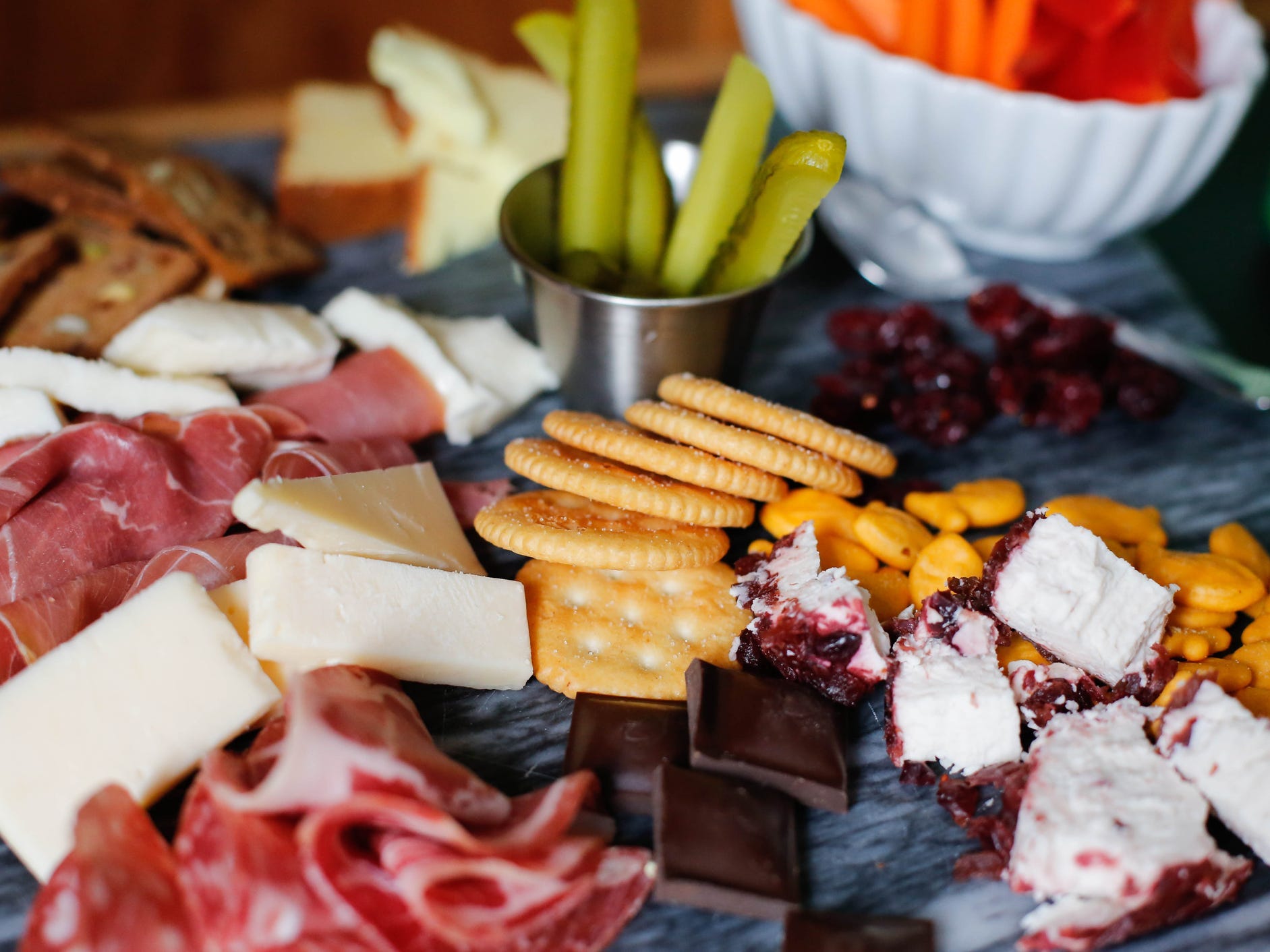 A charcuterie board with cheese, meats, crackers, and chocolate.