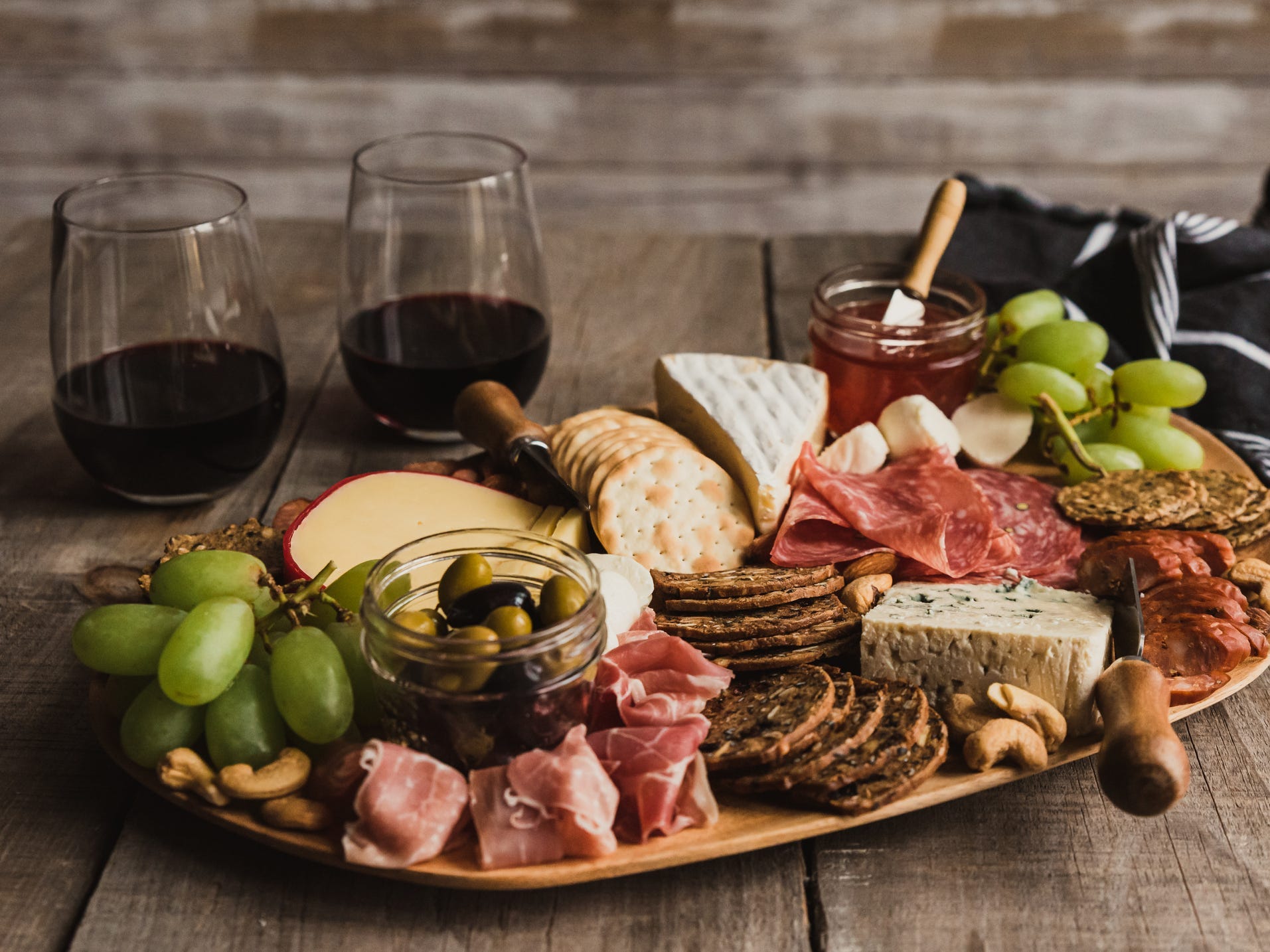 Close up of a charcuterie board with two glasses of wine in the background.