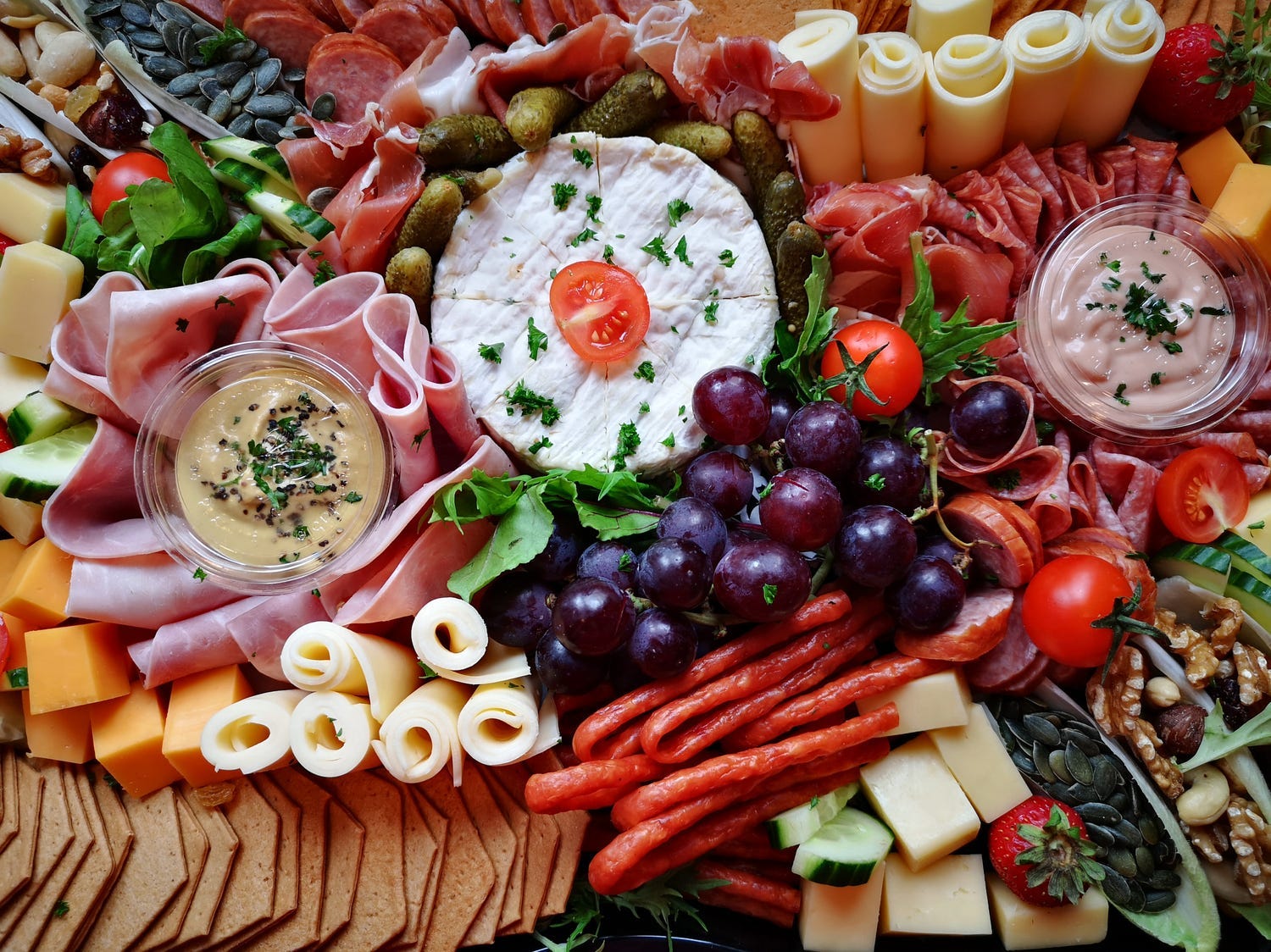 A charcuterie board with cheese, meats, fruits, and vegetables.