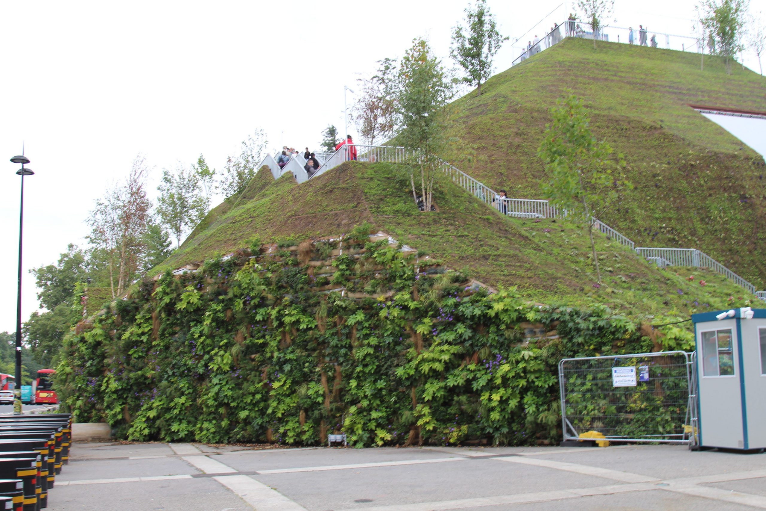 An artificial green hill is dotted with small trees on a grey concrete floor.