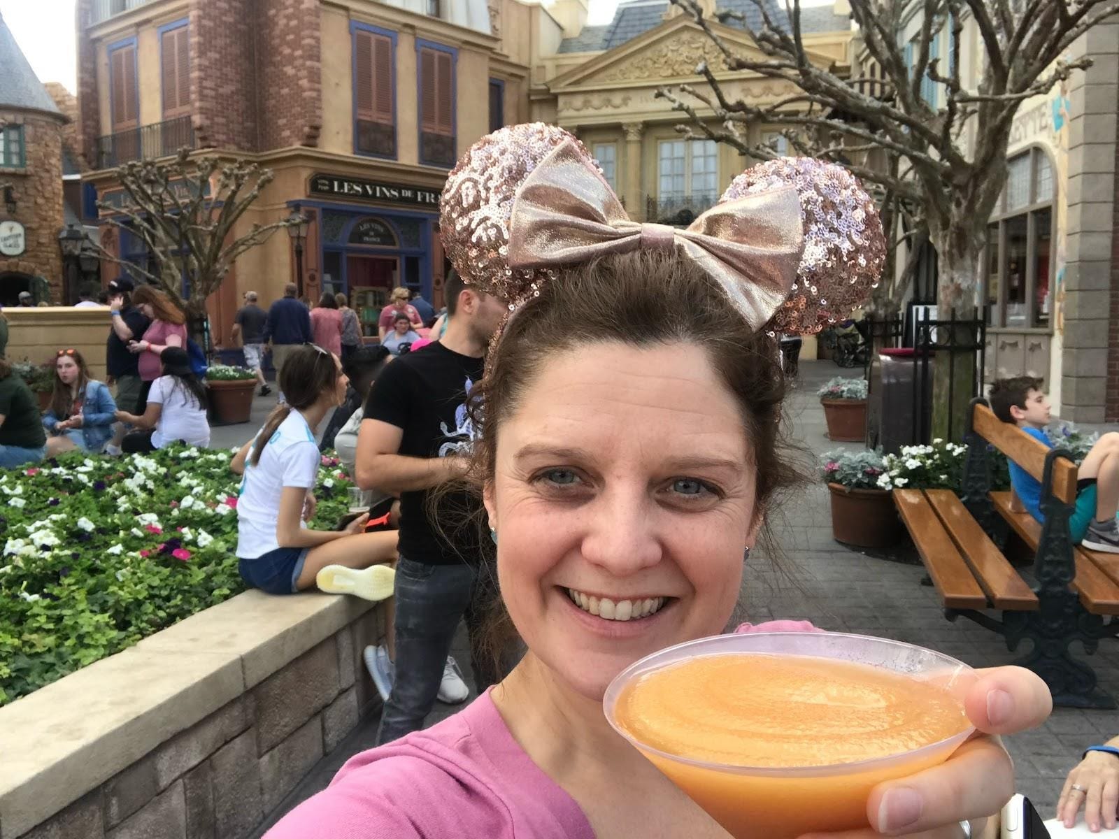 kari becker holding an orange drink in paris pavillion at epcot disney world