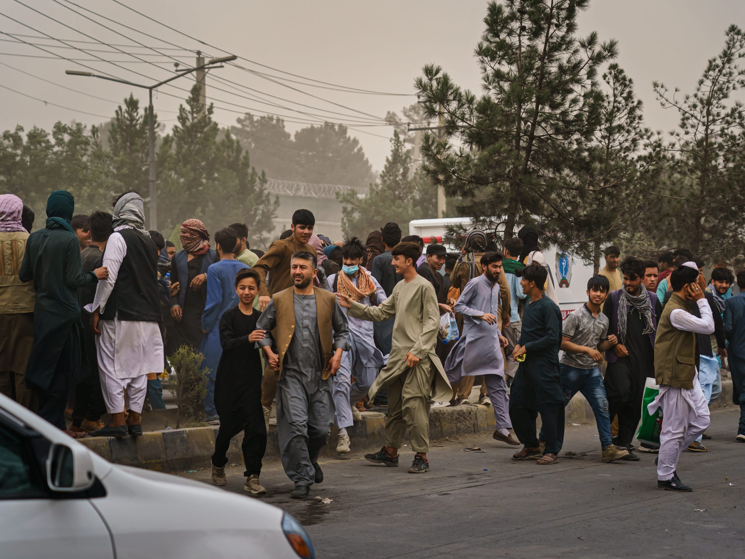 Afghans run away after Taliban fighters use guns fire, whips, sticks and sharp objects to maintain crowd control