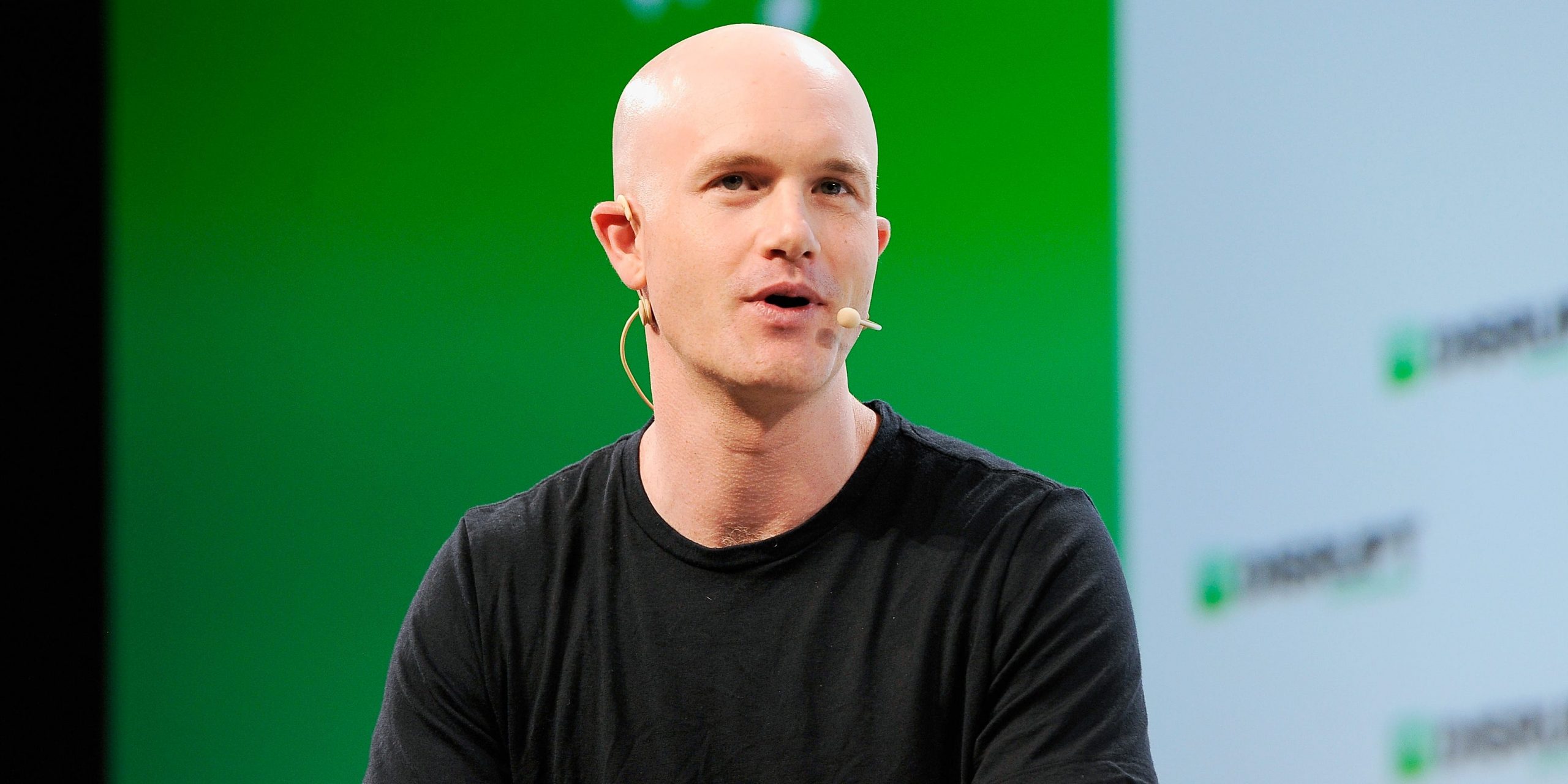 Coinbase Co-founder and CEO Brian Armstrong speaks on stage in front of a green background
