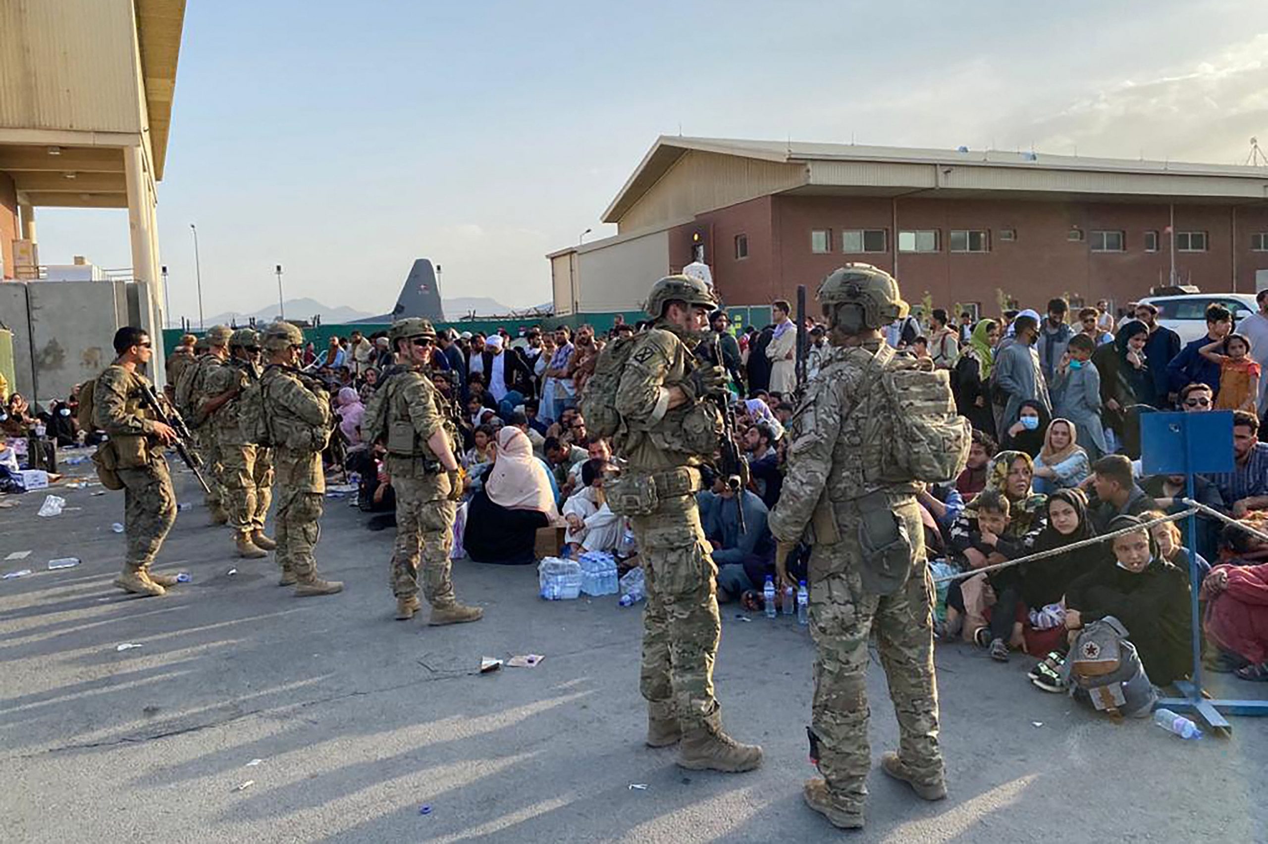 US soldiers stand in front of a crowd of Afghan people.