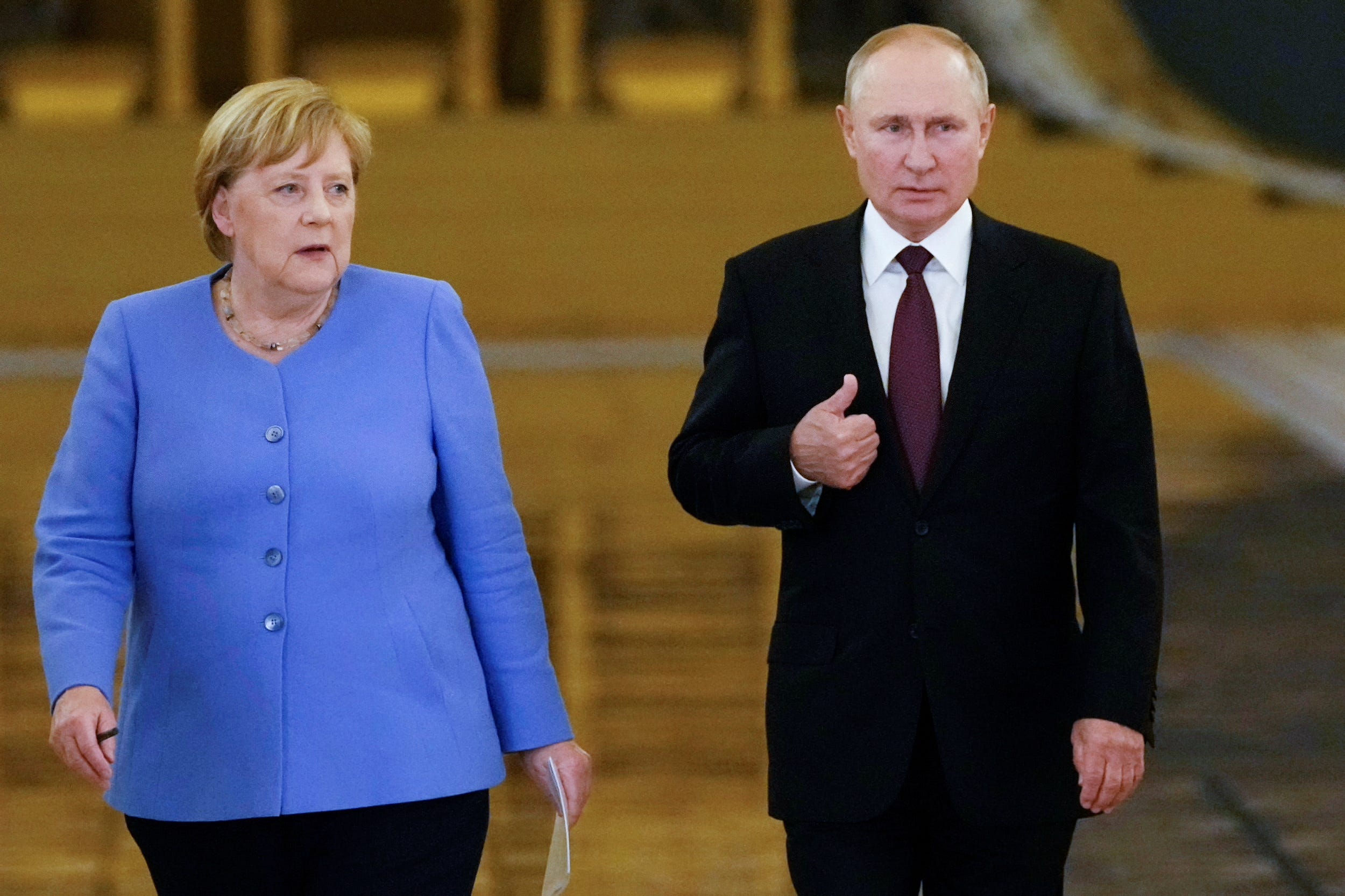 angela merkel in blue and vladimir putin in black walk together