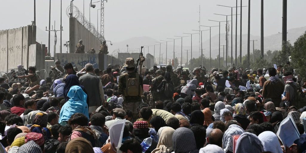 Afghans gather on a roadside near the military part of the airport in Kabul on August 20, 2021, hoping to flee from the country after the Taliban's military takeover of Afghanistan