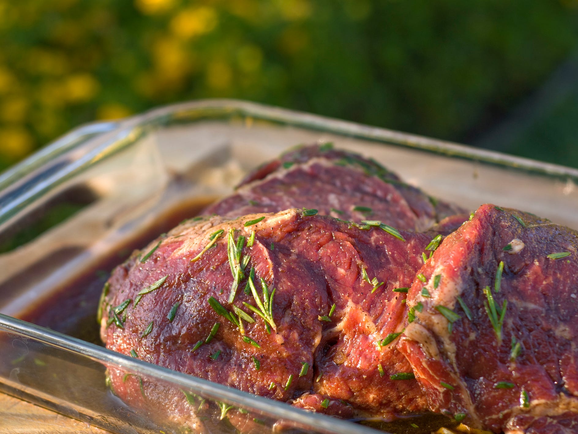 Raw steak marinating in a glass pan