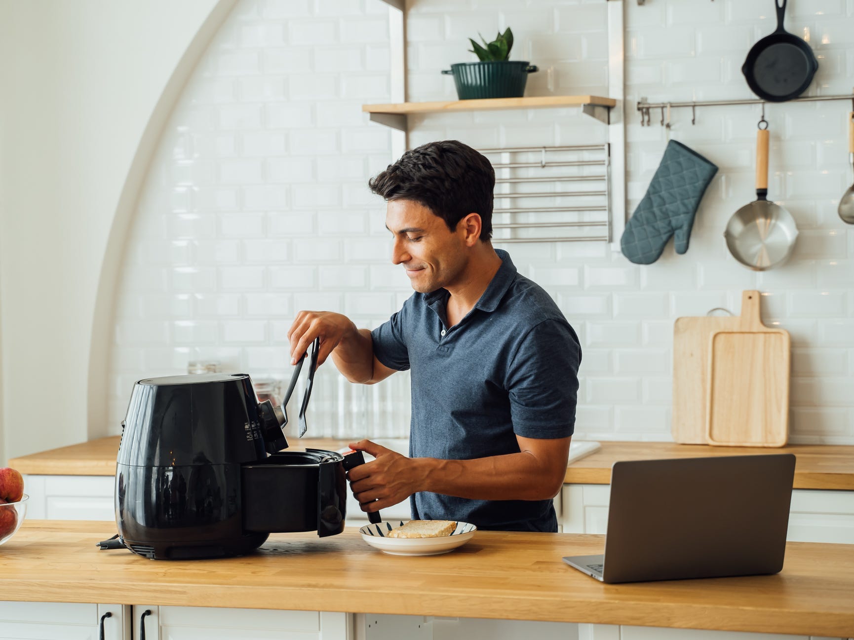 A man using an air fryer in a kitchen