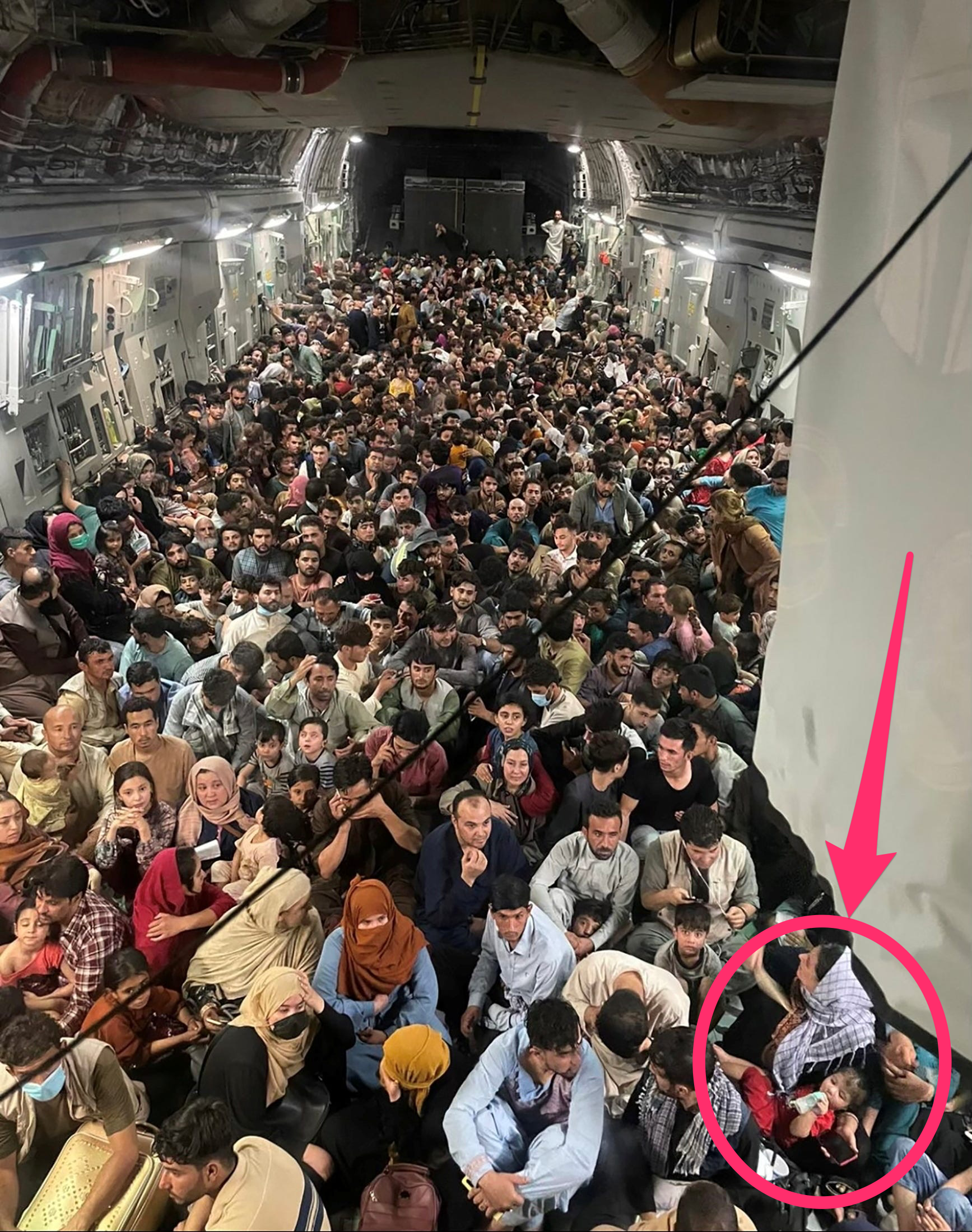 a mother nursing an infant is spotlighted on a us military cargo plane filled with hundreds of kabul evacuees