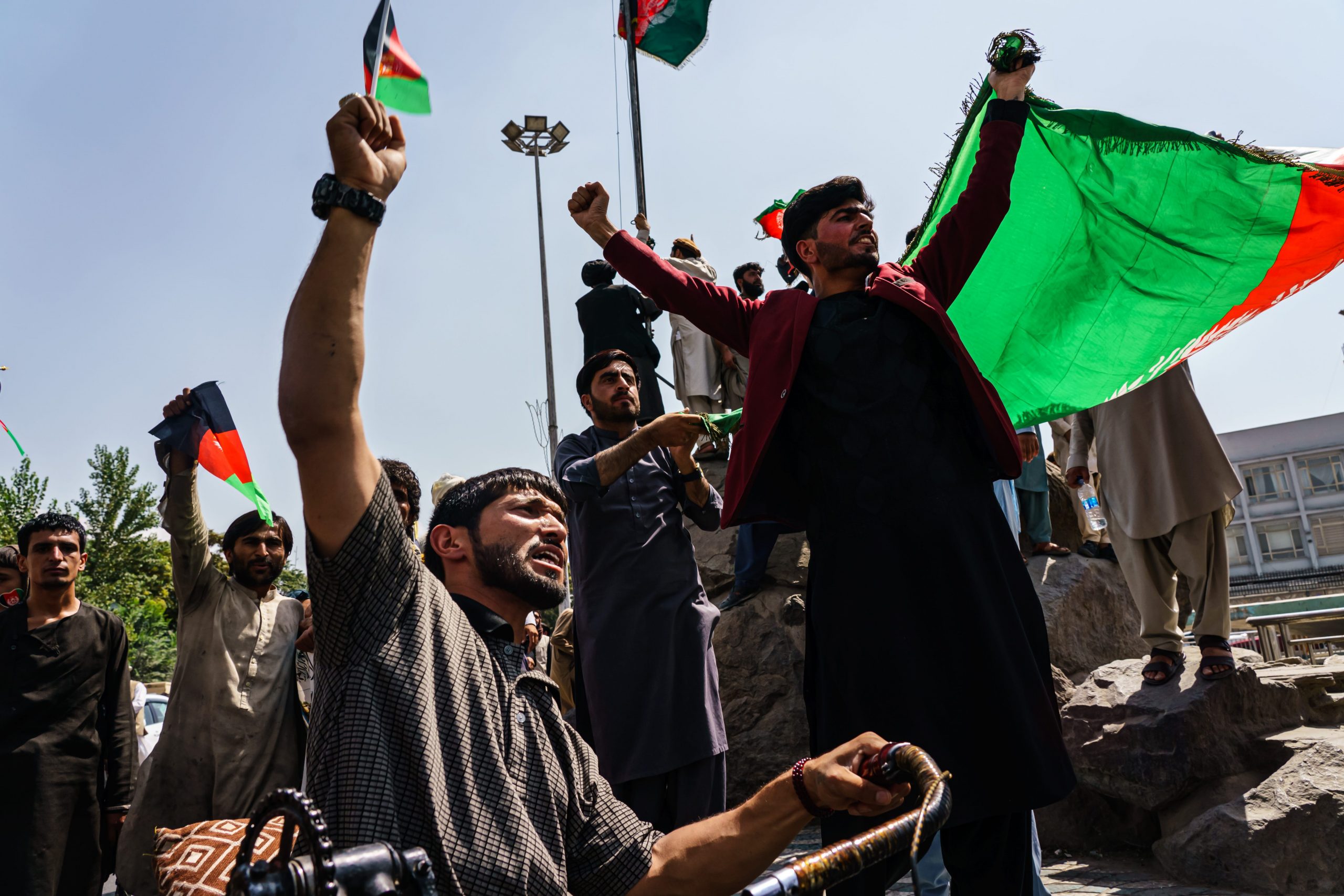 Afghans try to raise the national flag of the Islamic Republic of Afghanistan, despite the presence of Taliban fighters around them, during a rally for Independence Day at Pashtunistan Square in Kabul, Afghanistan, Thursday, Aug. 19, 2021