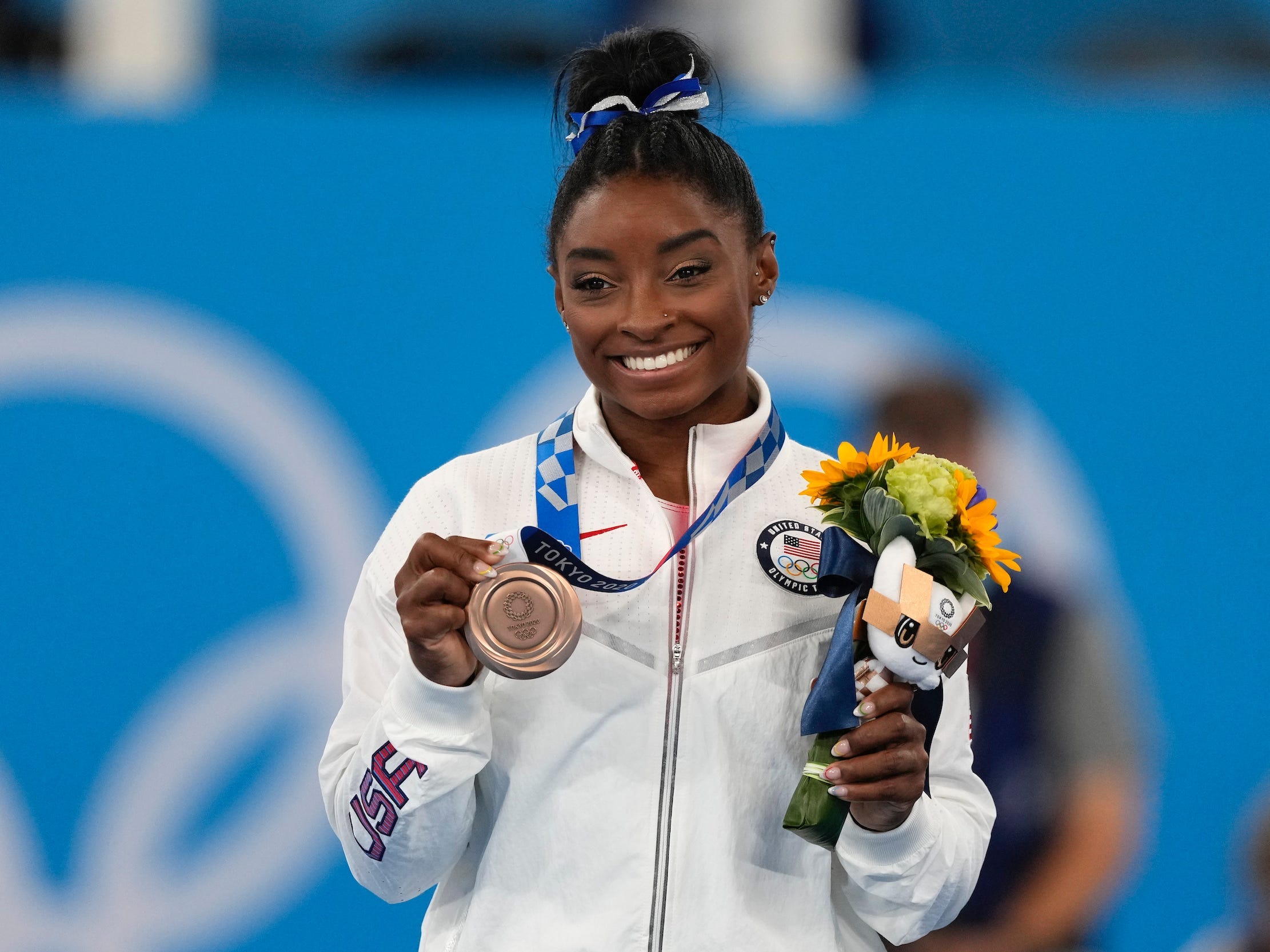 Simone Biles poses with her bronze medal from the balance beam final in Tokyo.