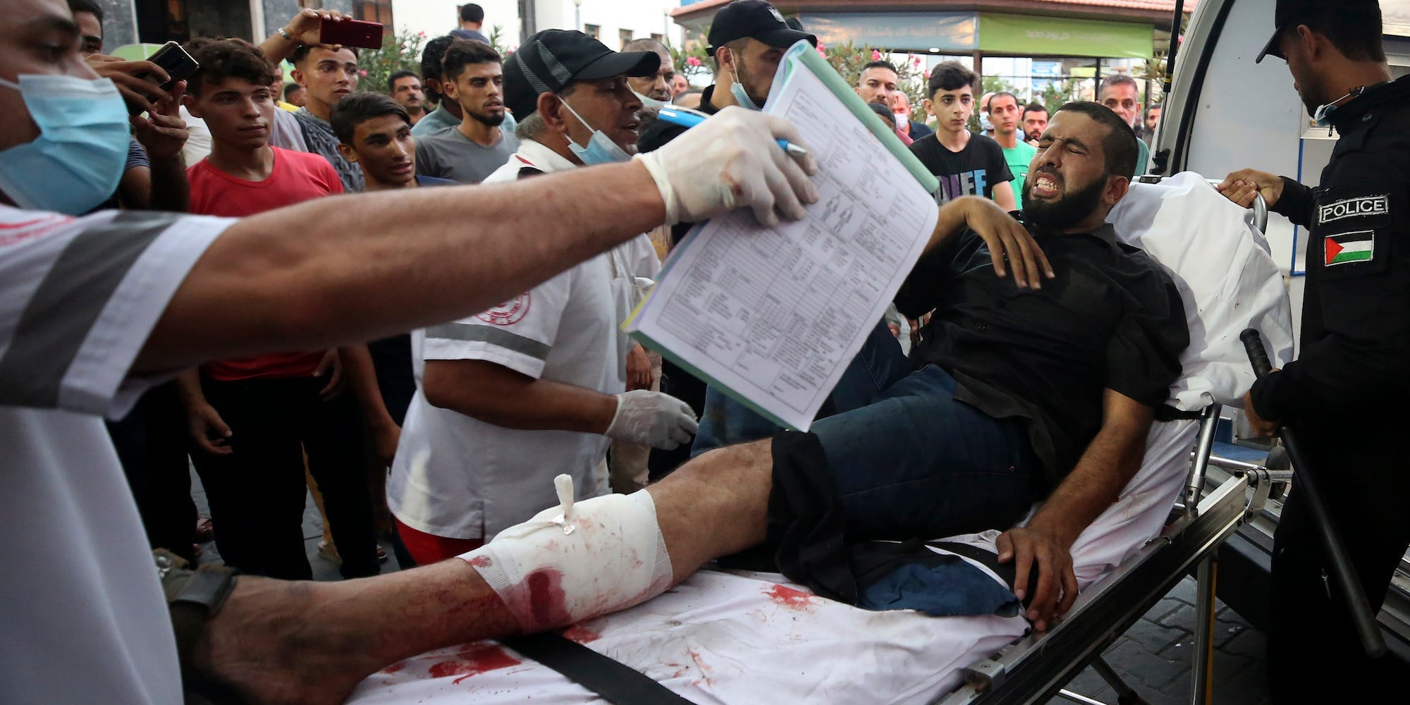 Medics move a wounded youth, who was shot by Israeli troops in his leg during a protest at the Gaza Strip's border with Israel, into the treatment room of Shifa hospital in Gaza City, Saturday, Aug. 21, 2021.