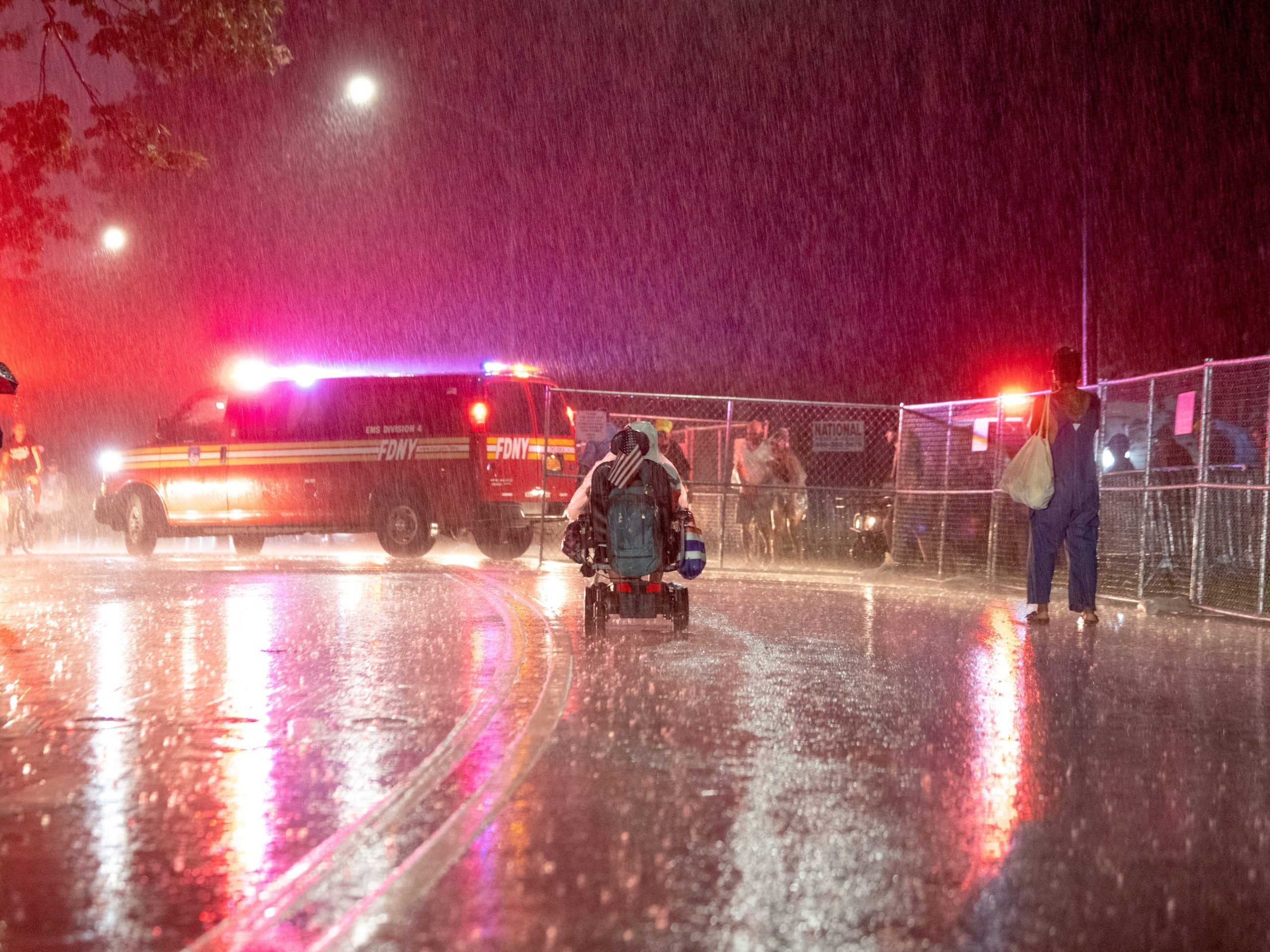 A person in a motorized wheel chair with an American flag leaves after the We Love NYC: The Homecoming Concert was cancelled due to storms from Hurricane Henri, on the Great Lawn in Central Park on August 21, 2021 in New York City