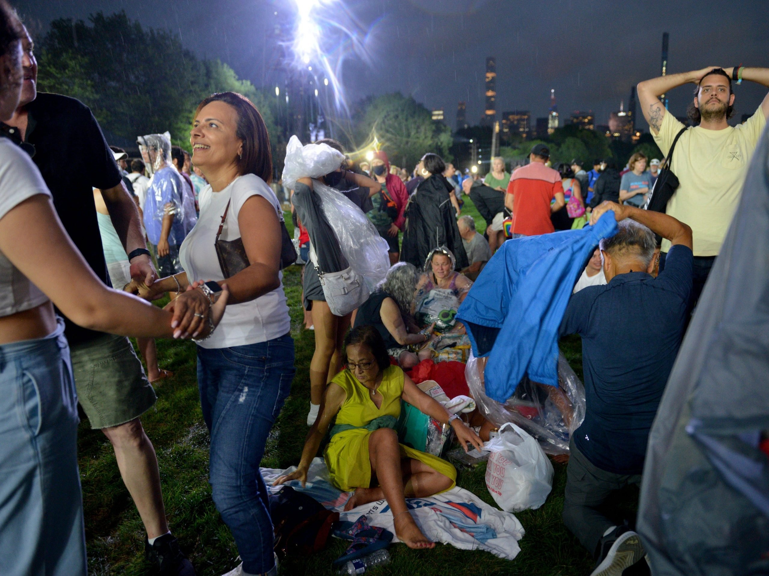 Concert goers puts on a rain poncho minutes before the We Love NYC: The Homecoming Concert was cancelled due to storms from Hurricane Henri at the Great Lawn in Central Park on August 21, 2021 in New York City.