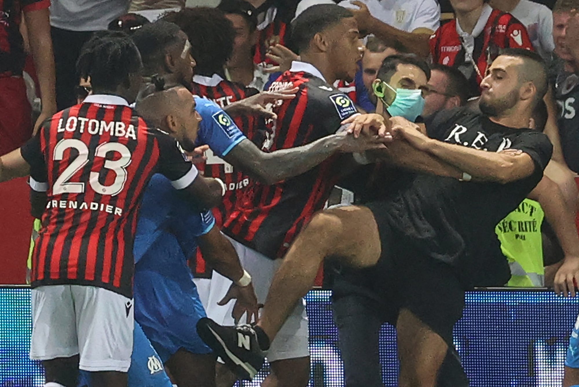 Marseille's French midfielder Dimitri Payet (2nd L) reacts as players from OGC Nice (red and black jersey) and Olympique de Marseille (blue jersey) stop a fan invading the pitch trying to kick Payet during the French L1 football match between OGC Nice and Olympique de Marseille