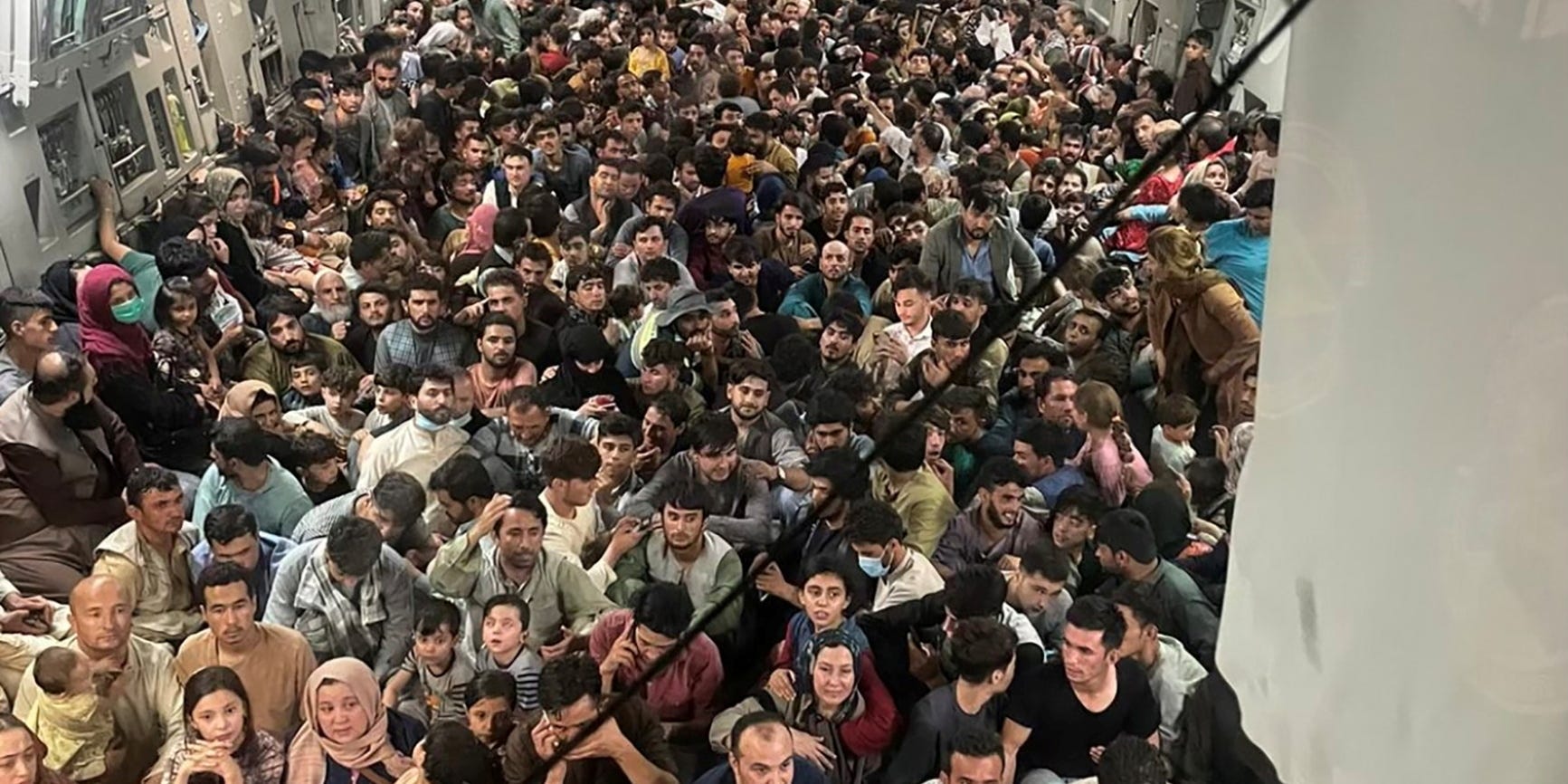 Hundreds of people sitting on the floor of a transport aircraft