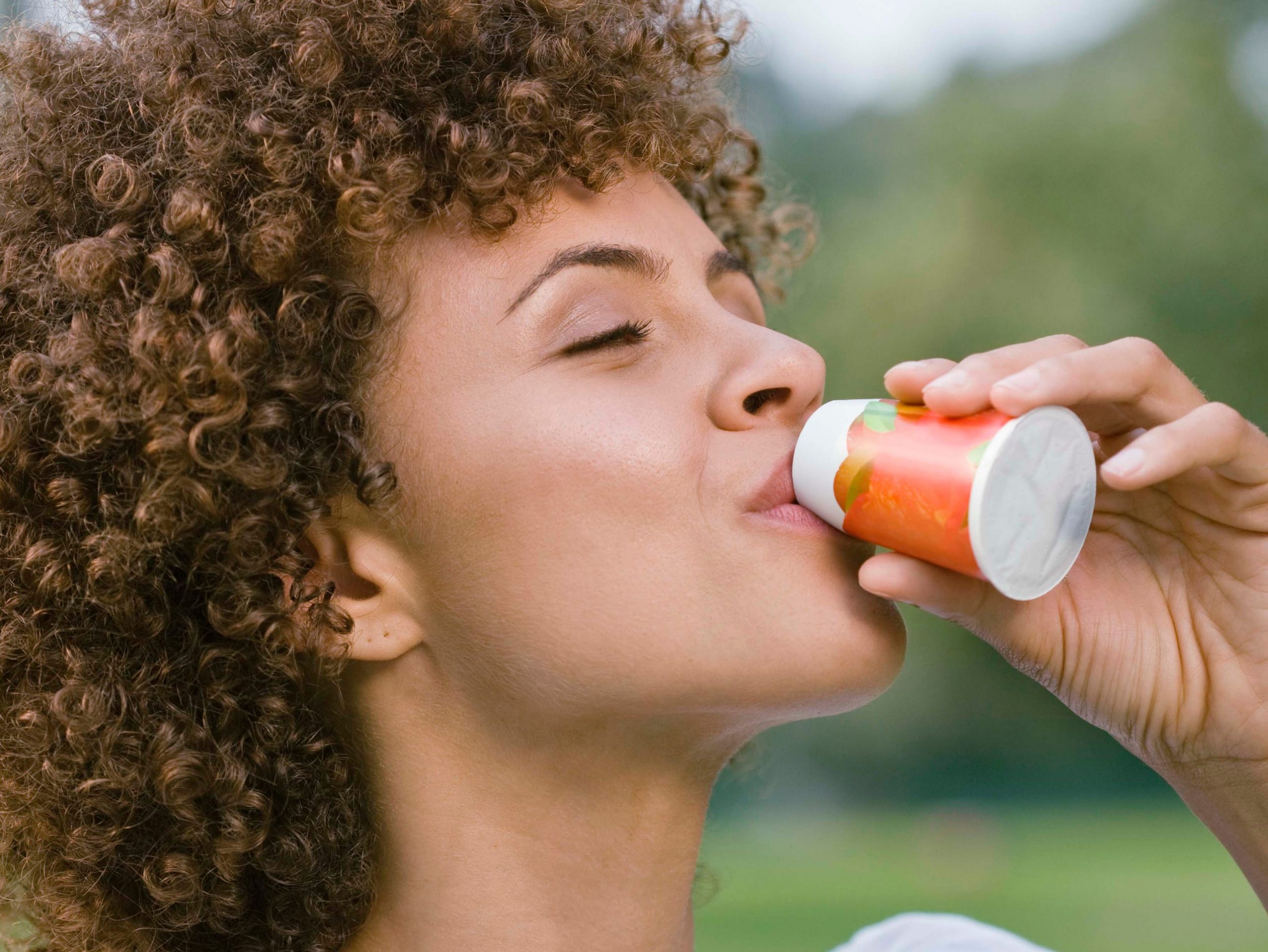 A woman drinking a supplement drink.