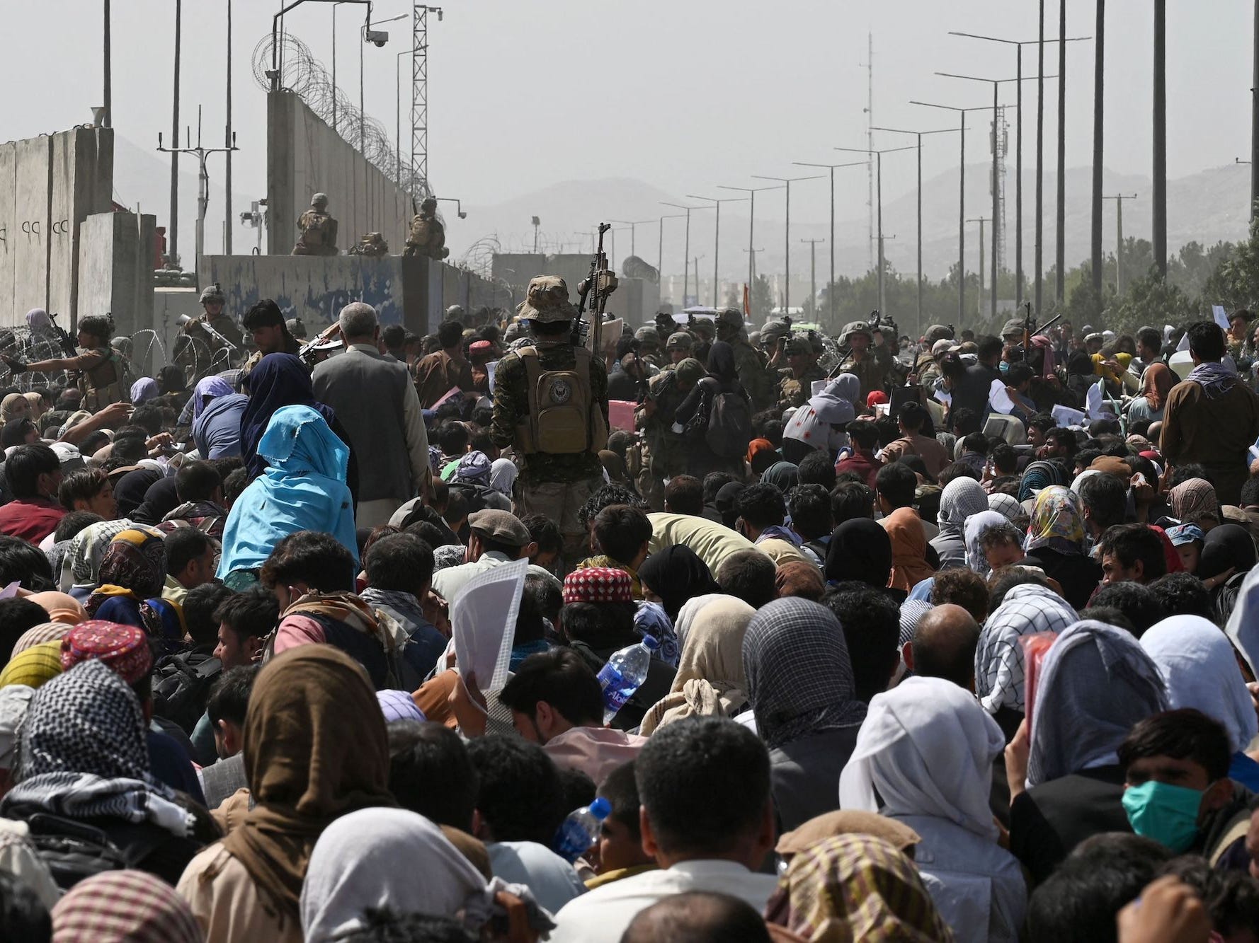 a large crowd gathers with fences in the distance