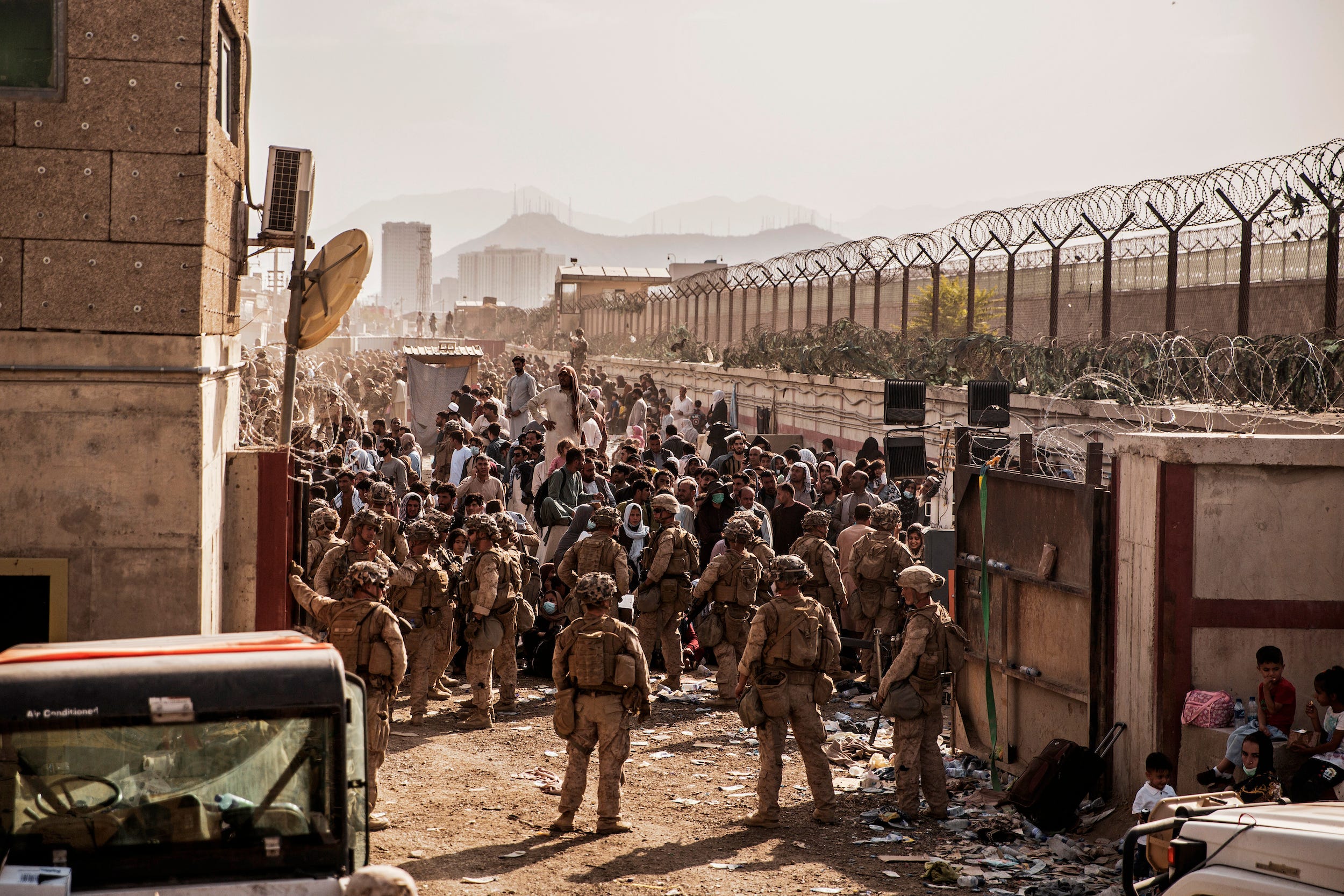 us soldiers face a crowd at a checkpoint with a large fence on either side of them