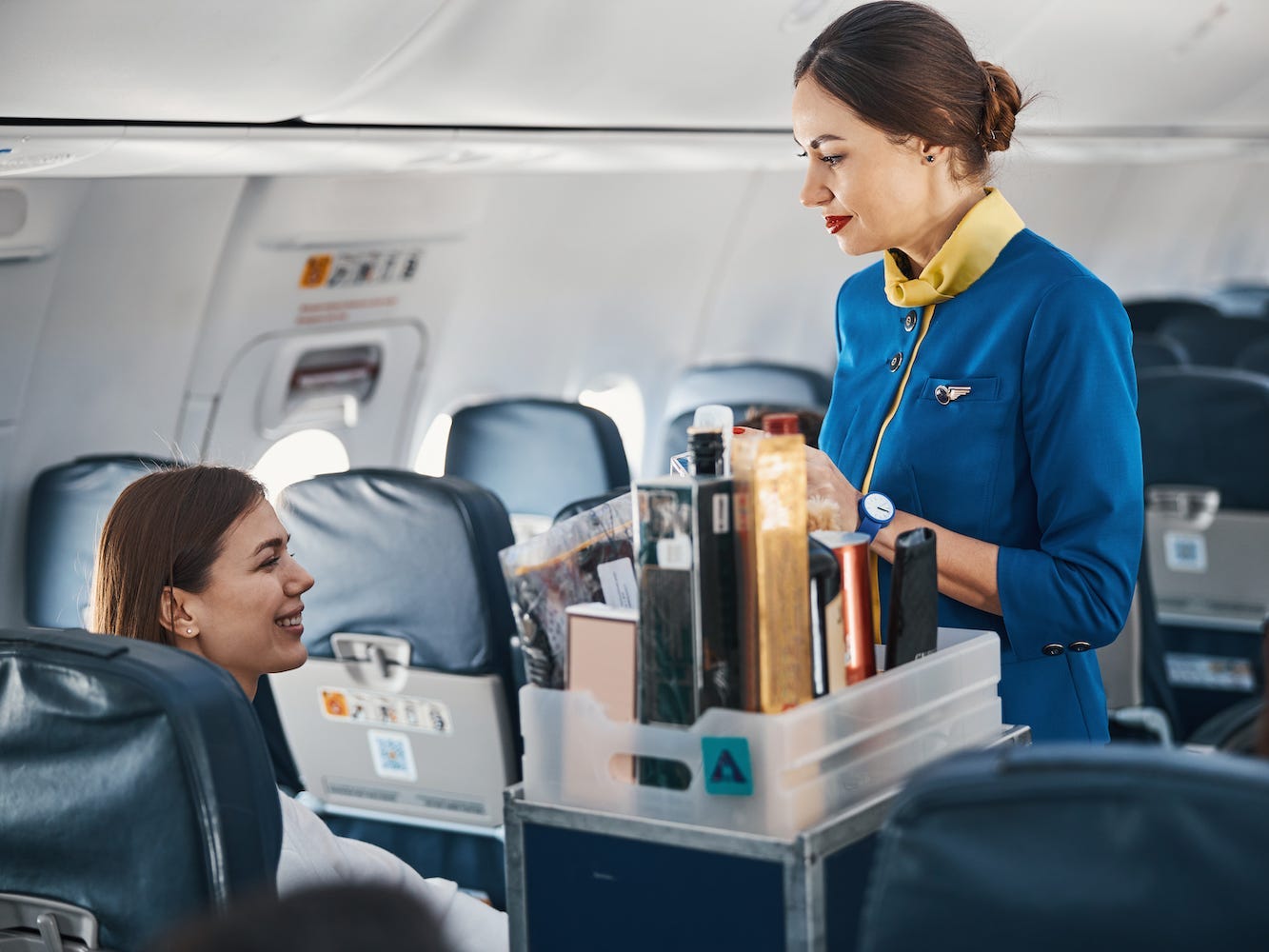A flight attendant serves a passenger a drink.