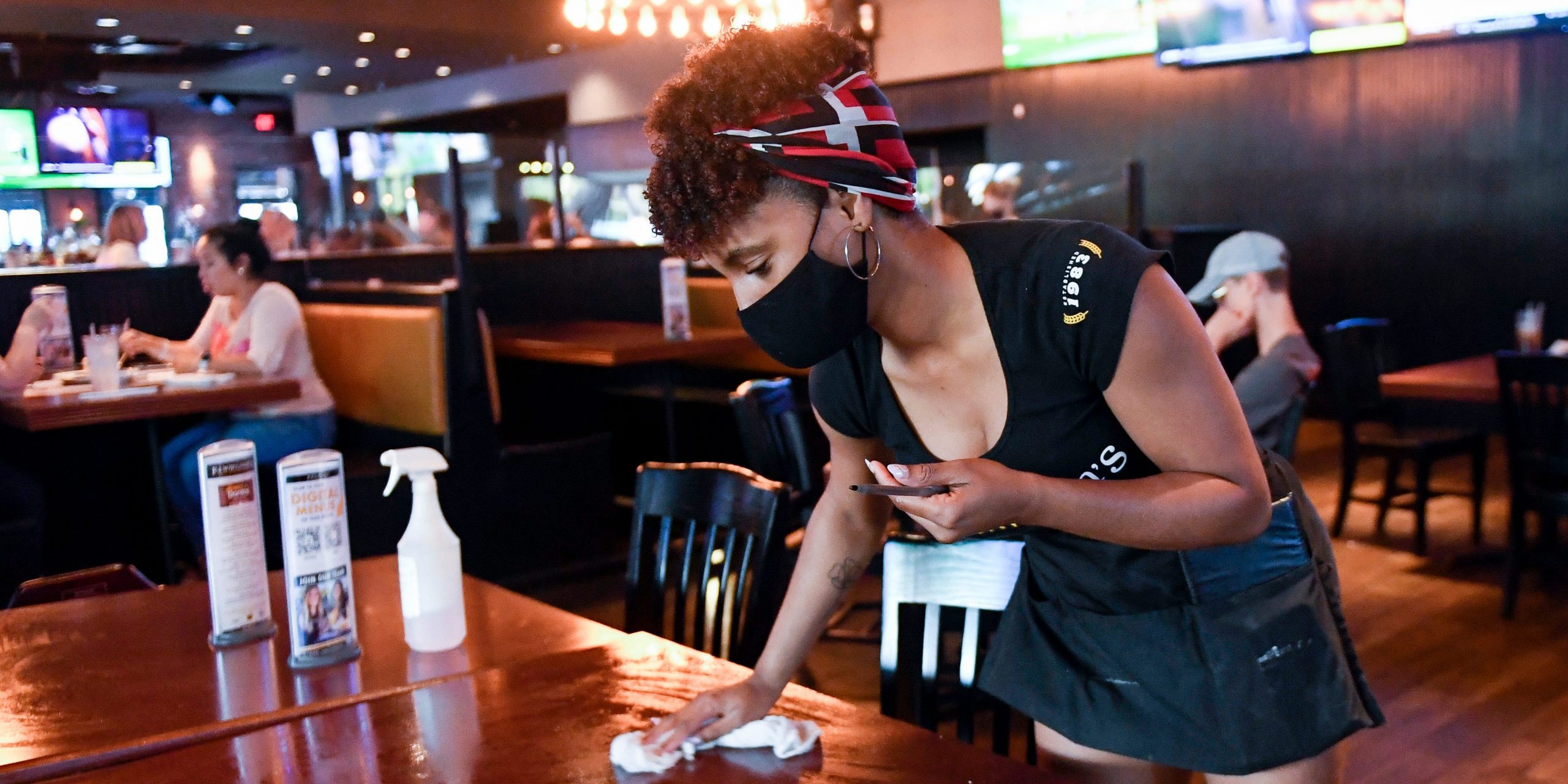 Restaurant server wipes down table at P.J. Whelihan's restaurant and pub in Spring Township Friday evening June 25, 2021