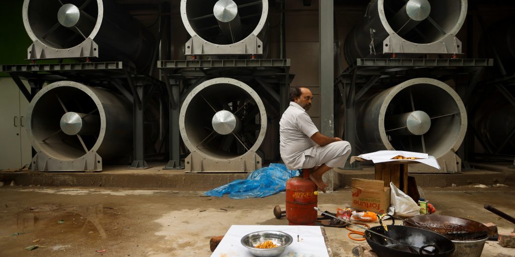 Een man zit naast de nieuwe smogtoren in New Delhi.