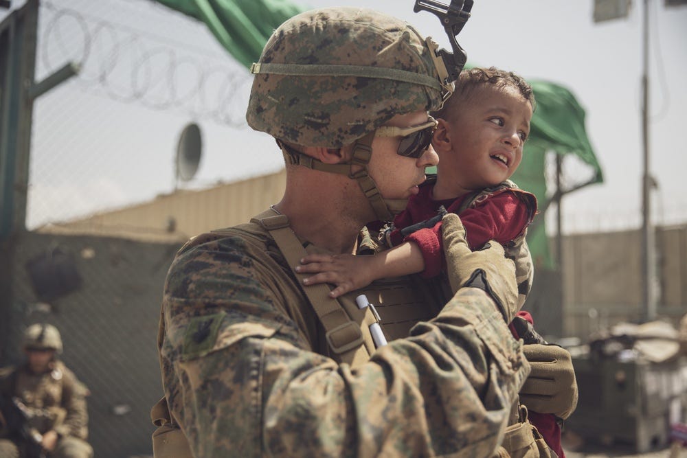 A Marine with the 24th Marine Expeditionary Unit (MEU) calms a crying toddler during an evacuation at Hamid Karzai International Airport, Afghanistan, Aug. 22, 2021.