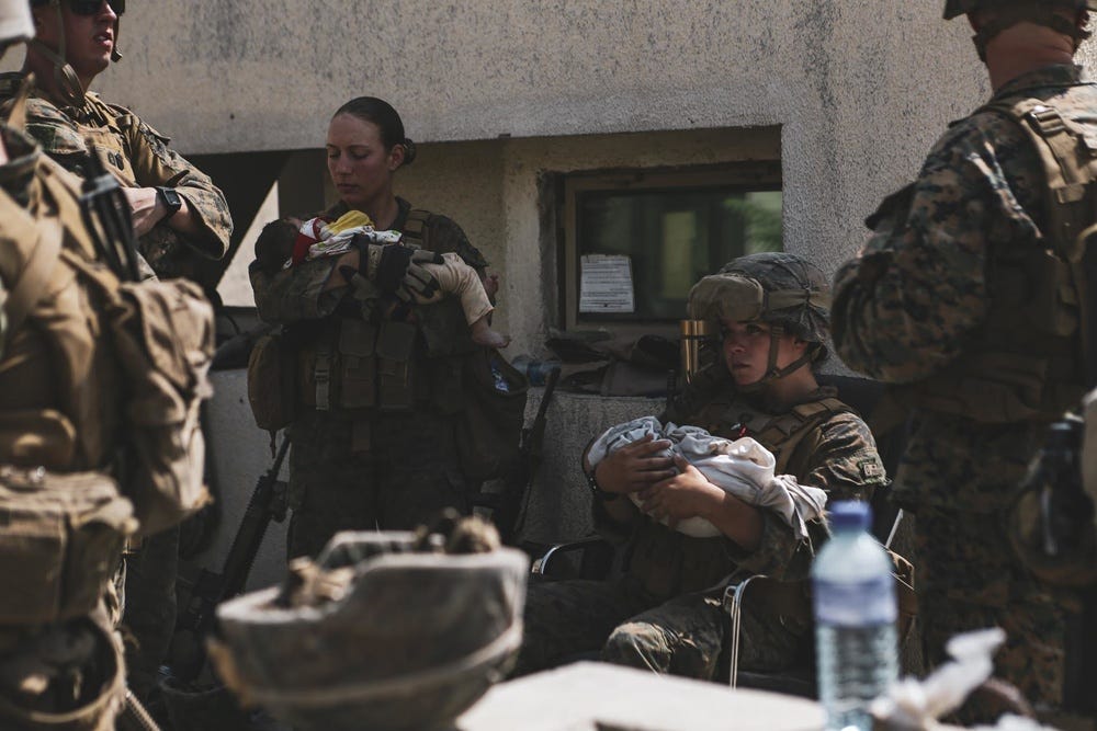 Marines assigned to the 24th Marine Expeditionary Unit (MEU) calm infants during an evacuation at Hamid Karzai International Airport, Kabul, Afghanistan, Aug. 20