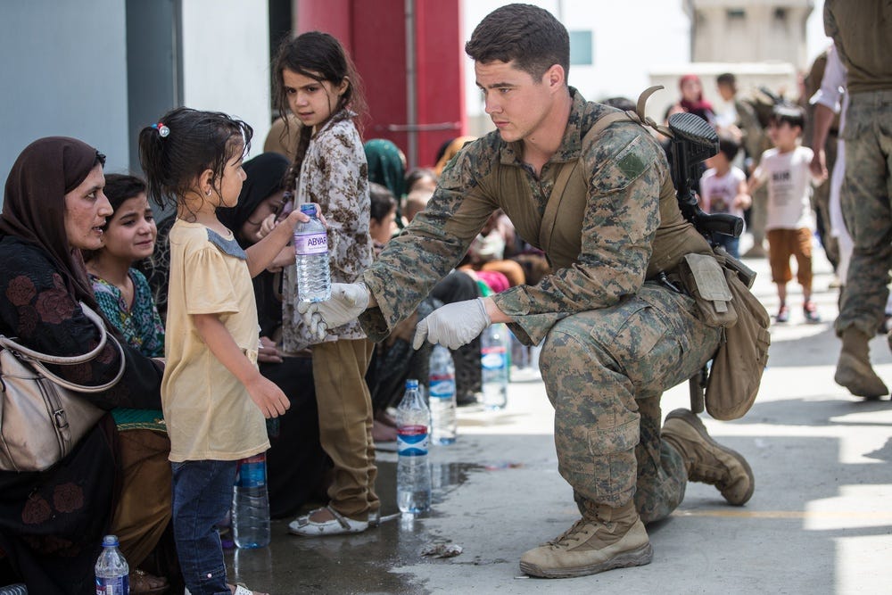 A Marine with the 24th Marine Expeditionary Unit (MEU) provides fresh water to a child during an evacuation at Hamid Karzai International Airport, Kabul, Afghanistan, Aug. 20