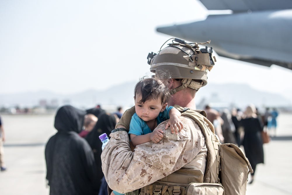 A Marine with Special Purpose Marine Air-Ground Task Force-Crisis Response-Central Command (SPMAGTF-CR-CC) calms an infant during an evacuation at Hamid Karzai International Airport, Kabul, Afghanistan, Aug. 21