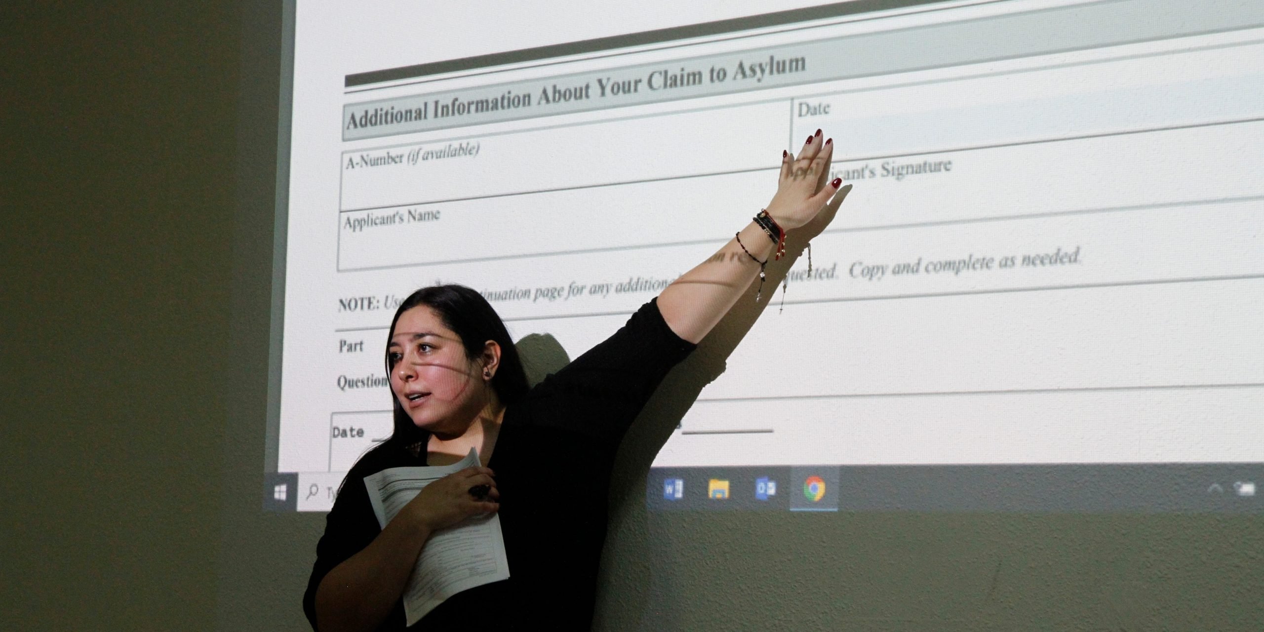 A woman points to a field on an aslyum application.