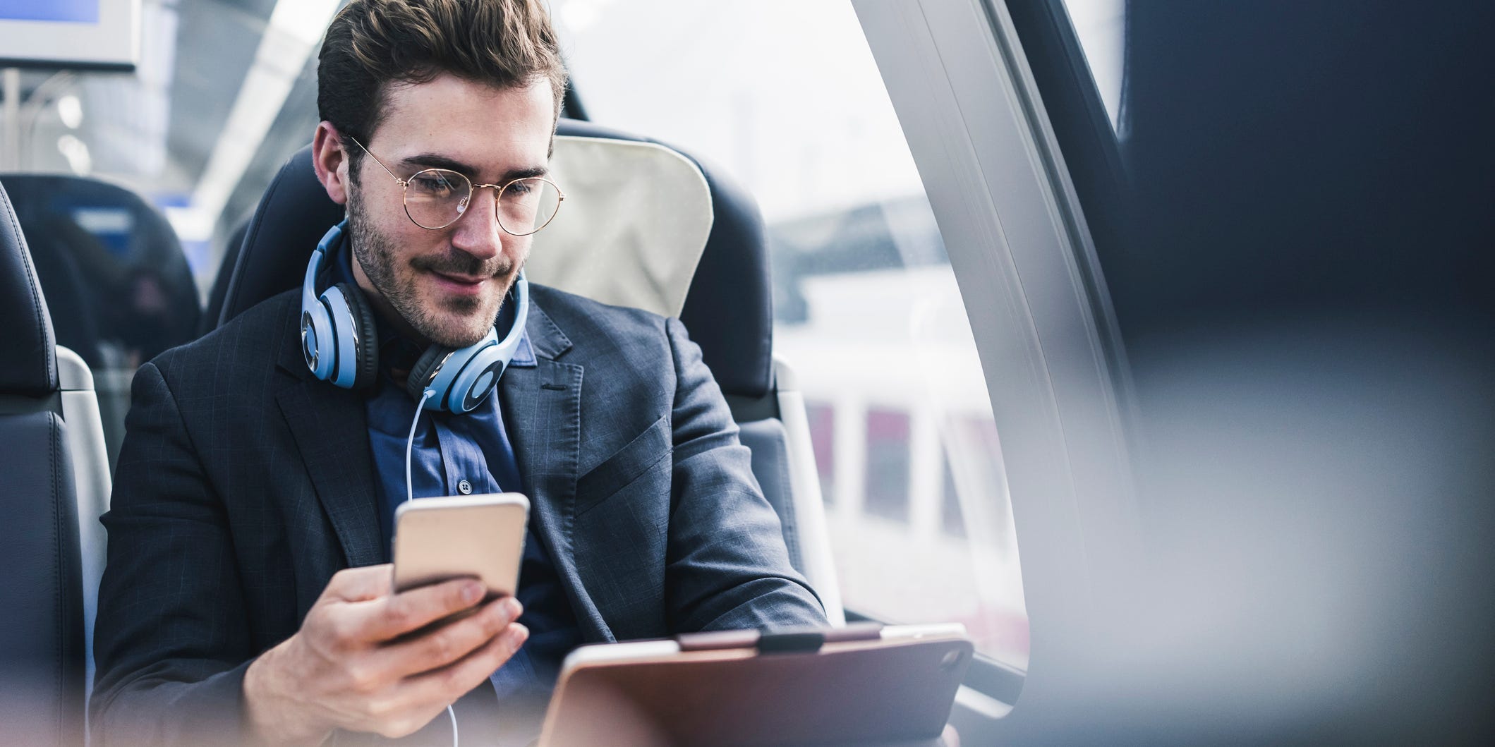 Man on train using tablet and smartphone