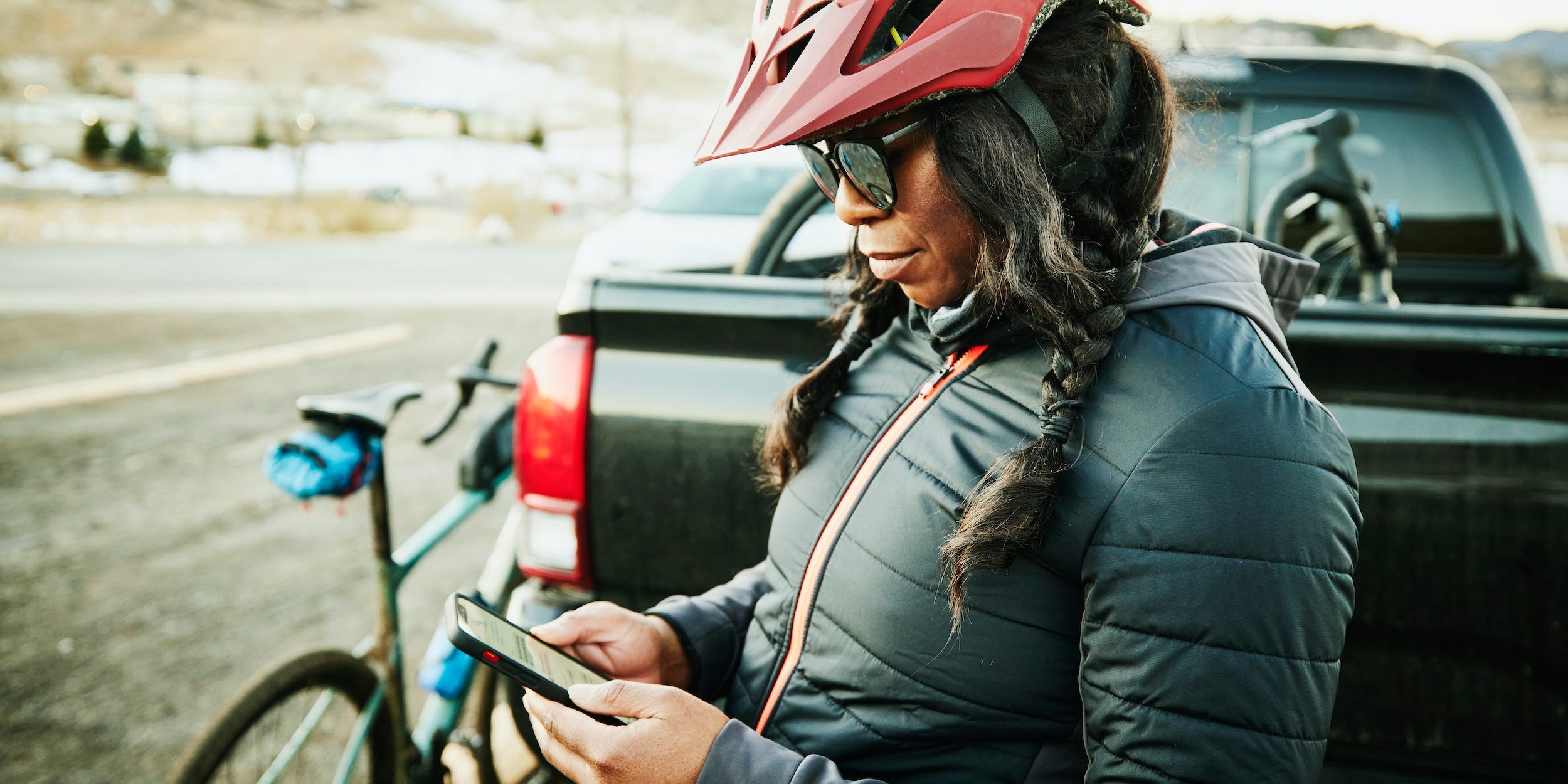 biker on side of road looking at phone with helmet on