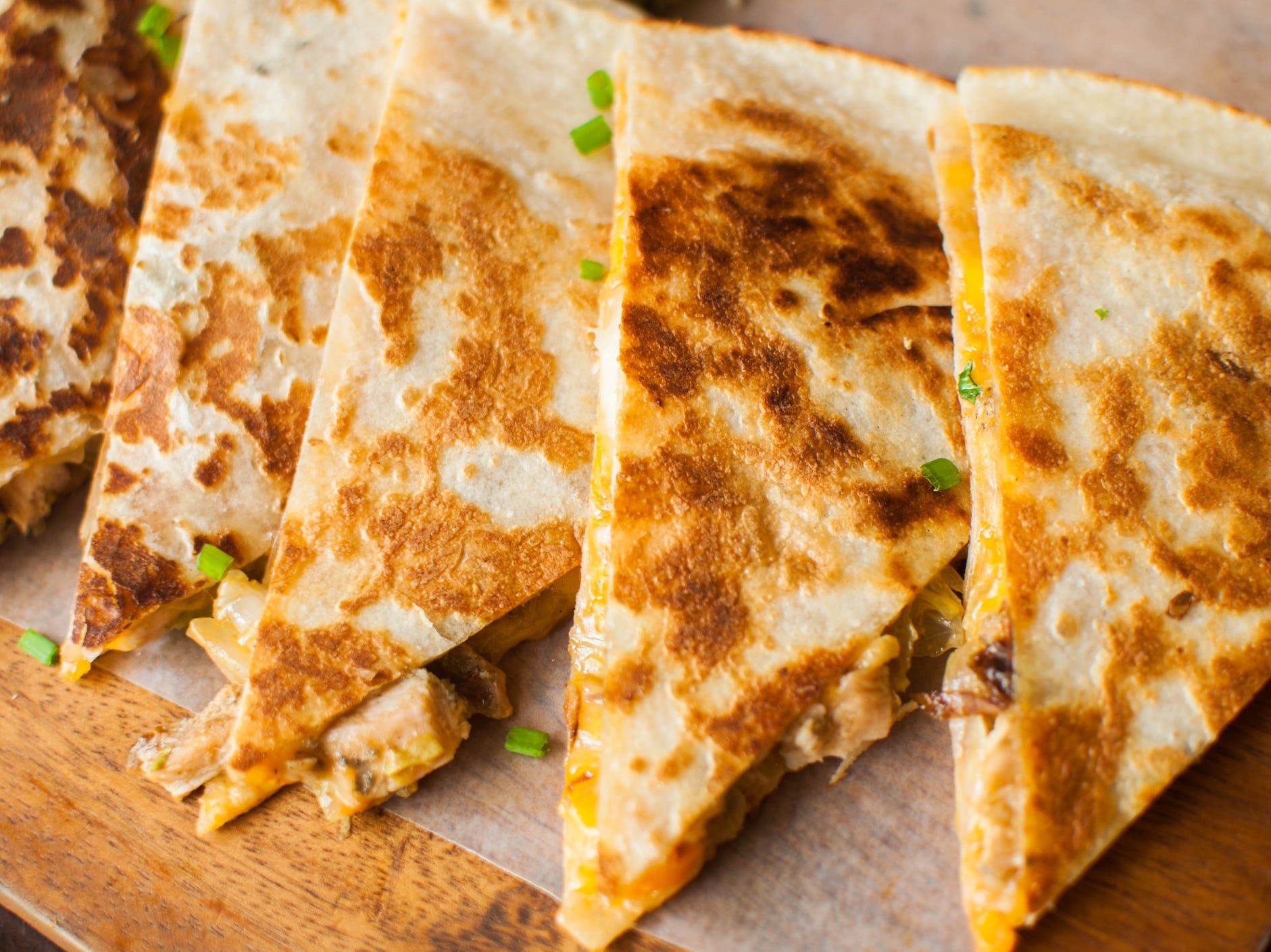 A chicken and cheese quesadilla sliced into wedges and laid out in a line