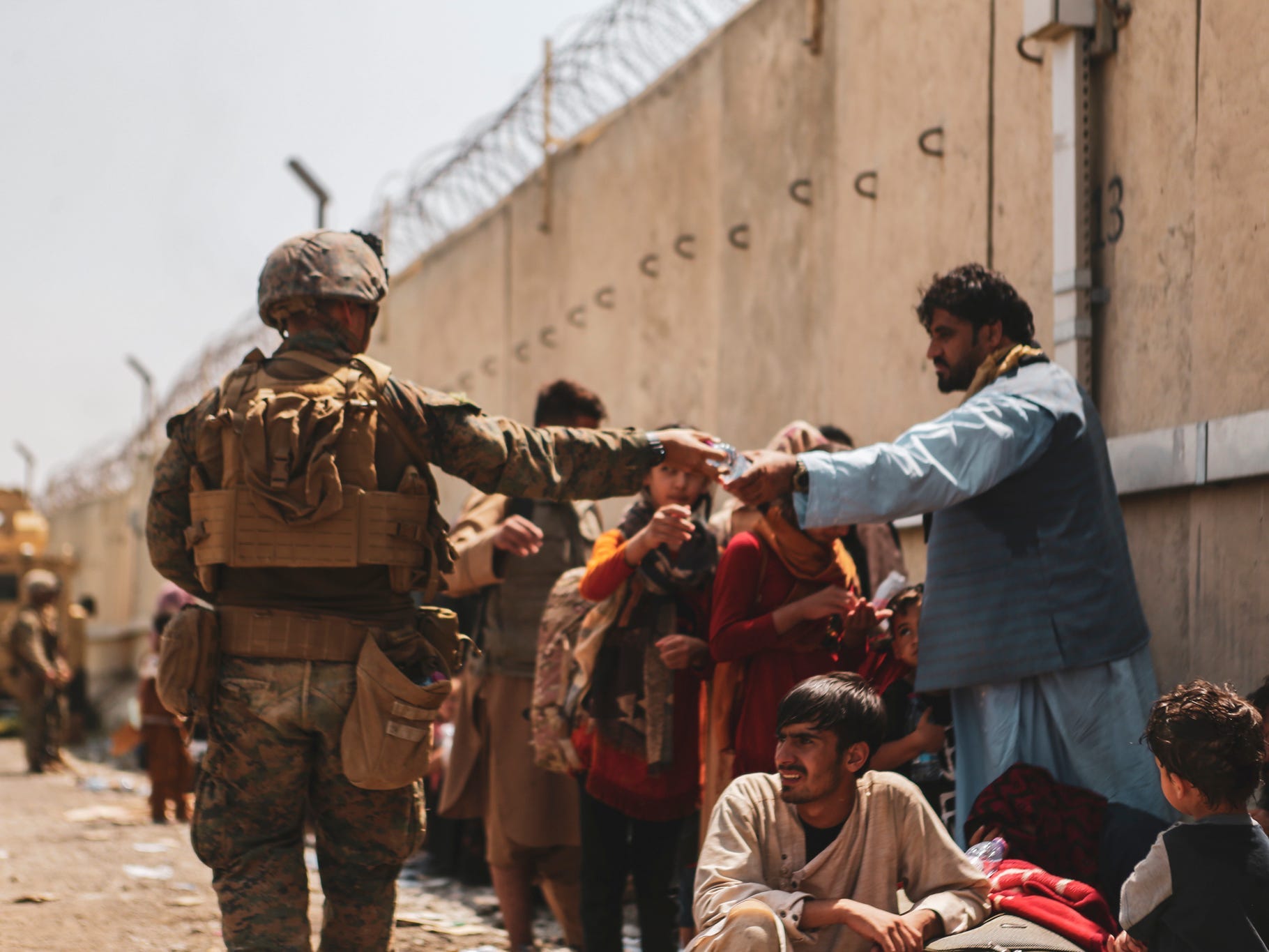 This handout image shows A Marine with the 24th Marine Expeditionary unit (MEU) passes out water to evacuees during an evacuation at Hamid Karzai International Airport, Kabul, Afghanistan, August 22.