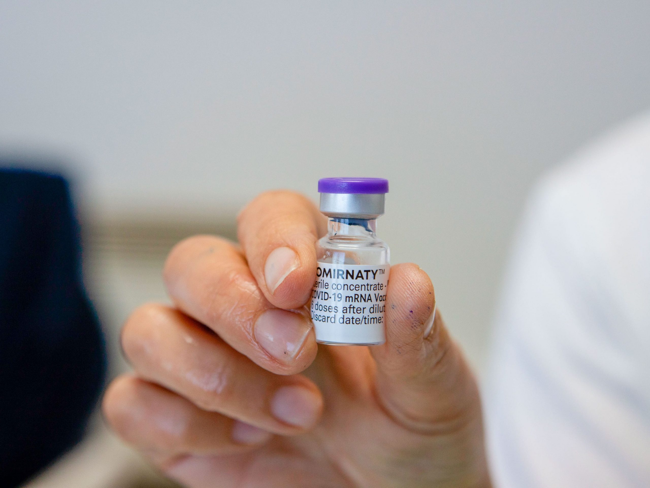 A health worker seen holding a vial containing the Cominarty vaccine.