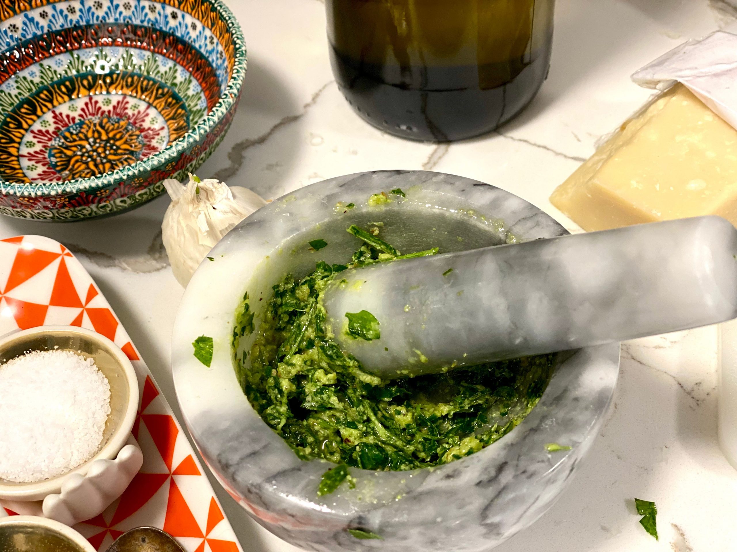 Pesto getting made using a mortar and pestle.