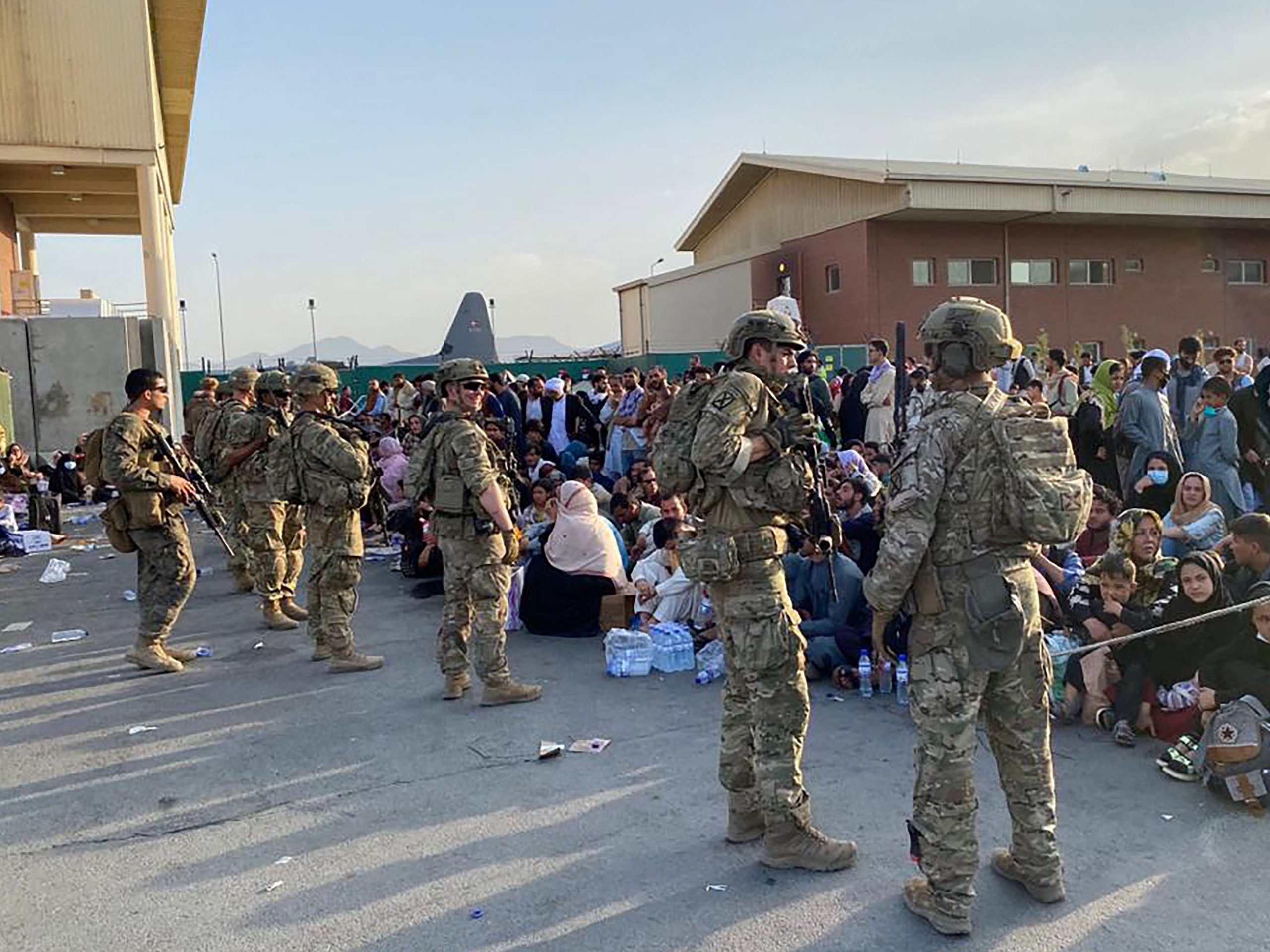 US soldiers stand in front of a crowd of Afghan people.