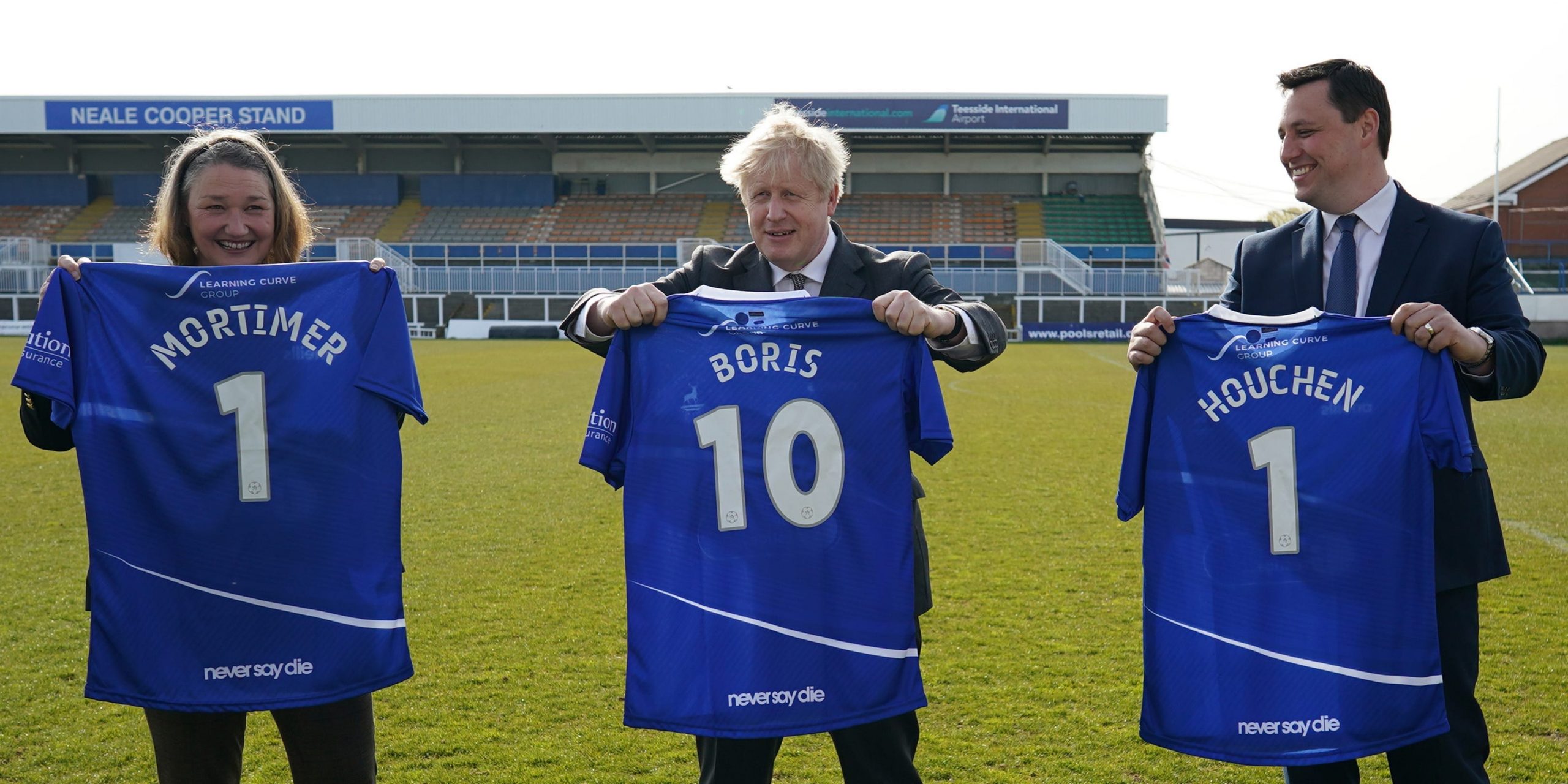 Jill Mortimer holds a football t-shirt with her surname and the number 1; Boris Johnson the same with a shirt with the number 10; Ben Houchen the same with a number 1.