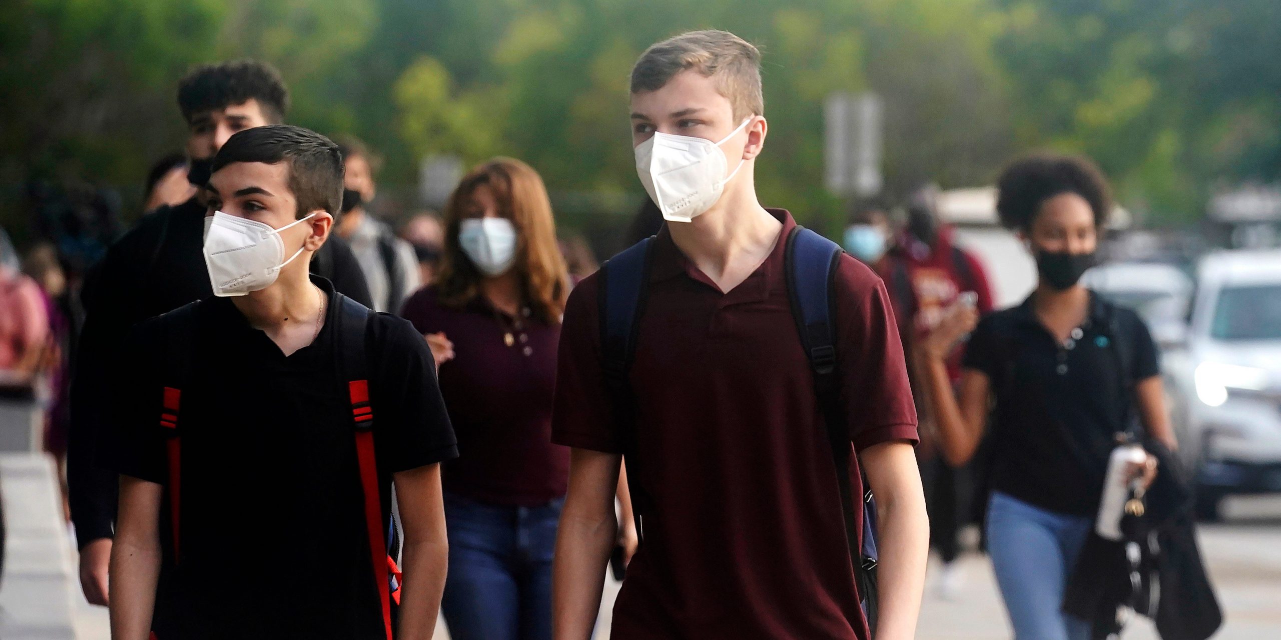 High school students wear mask while walking into school.