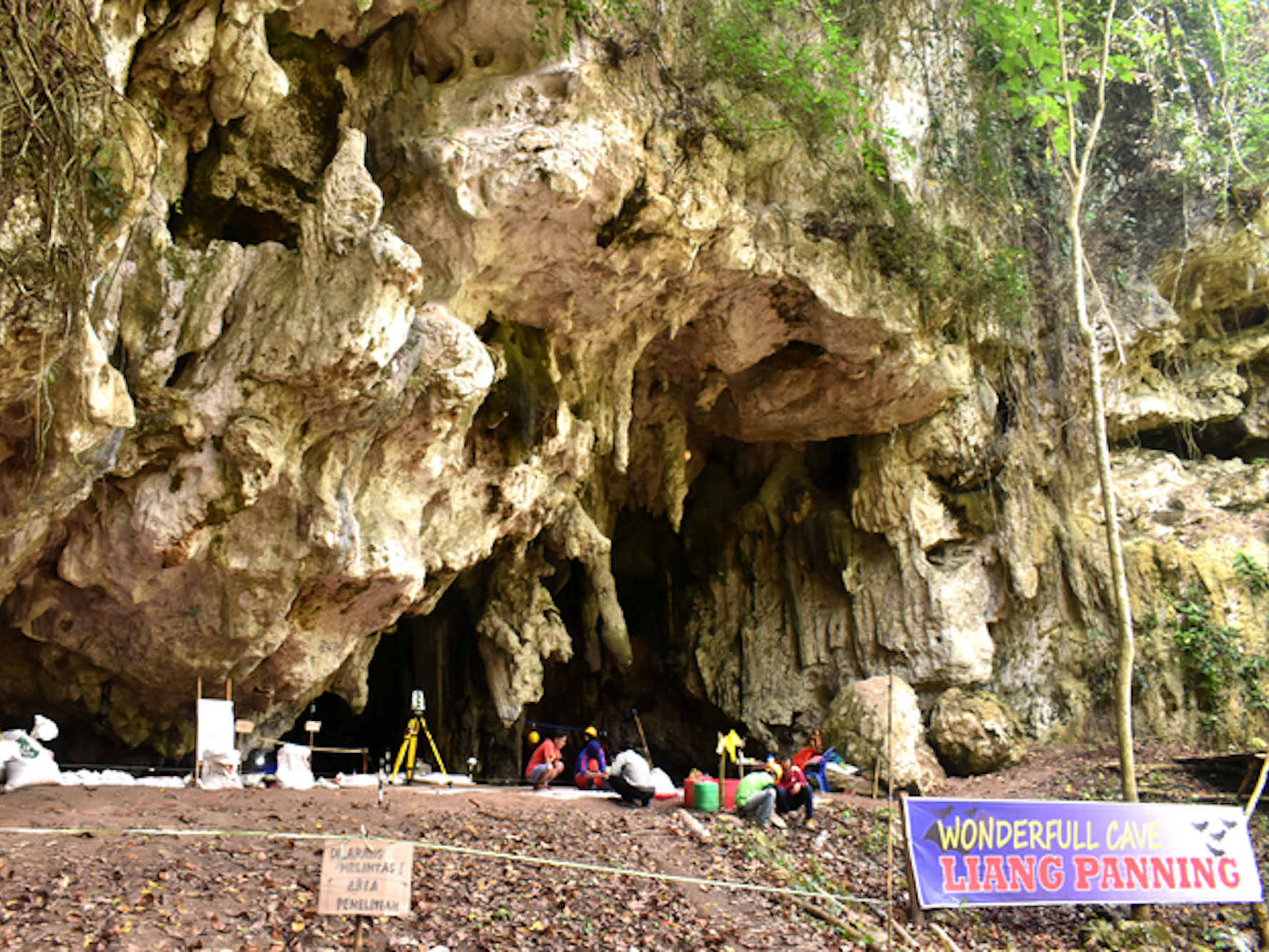 a picture shows a cave in a protruding rugged cliff of white stone. A sign reads: "Wonderful cave, Liang Panninge".